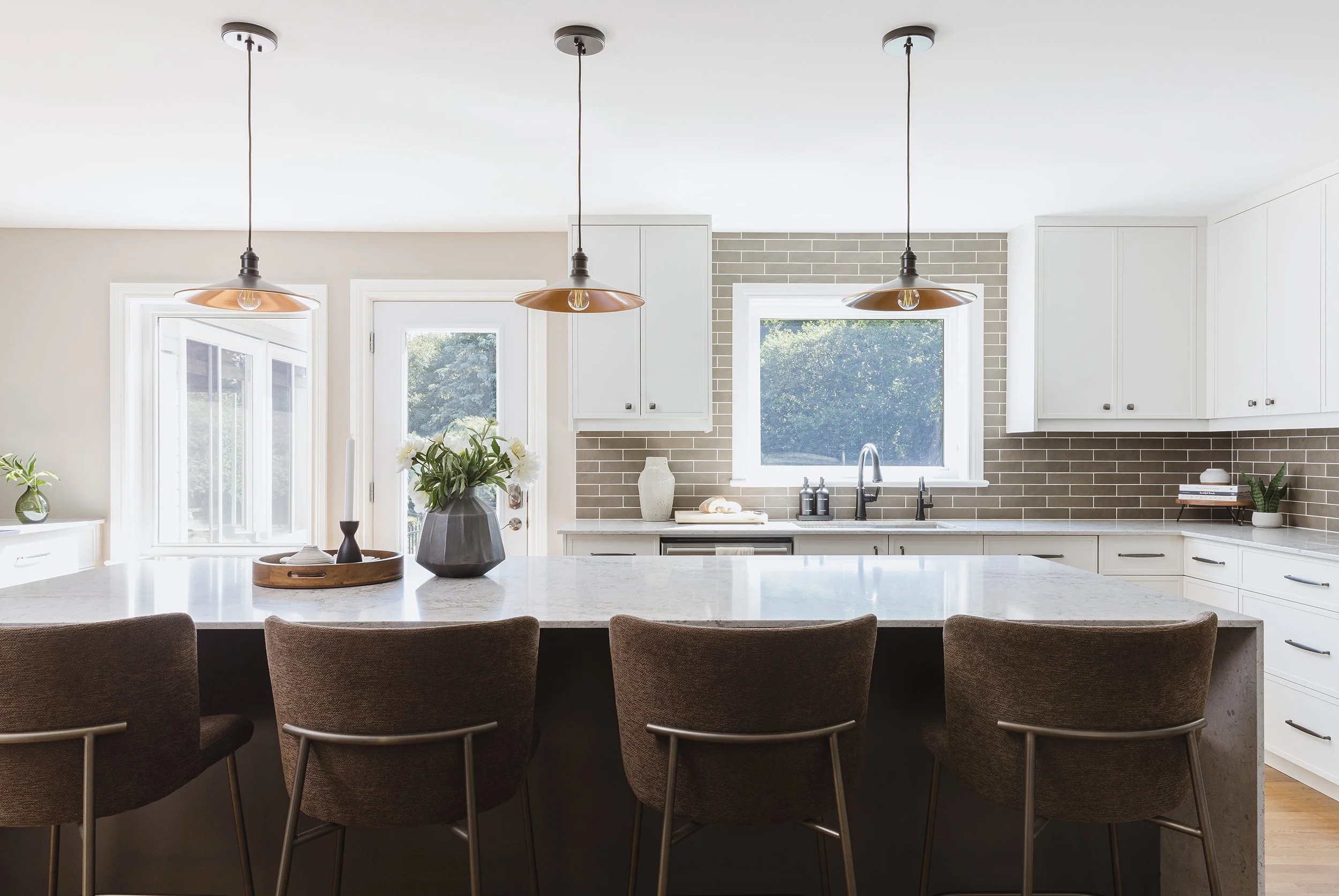 Custom kitchen design for an Ottawa family home featuring light coloured skinny shaker cabinets, a dark brown backsplash and a brown island.