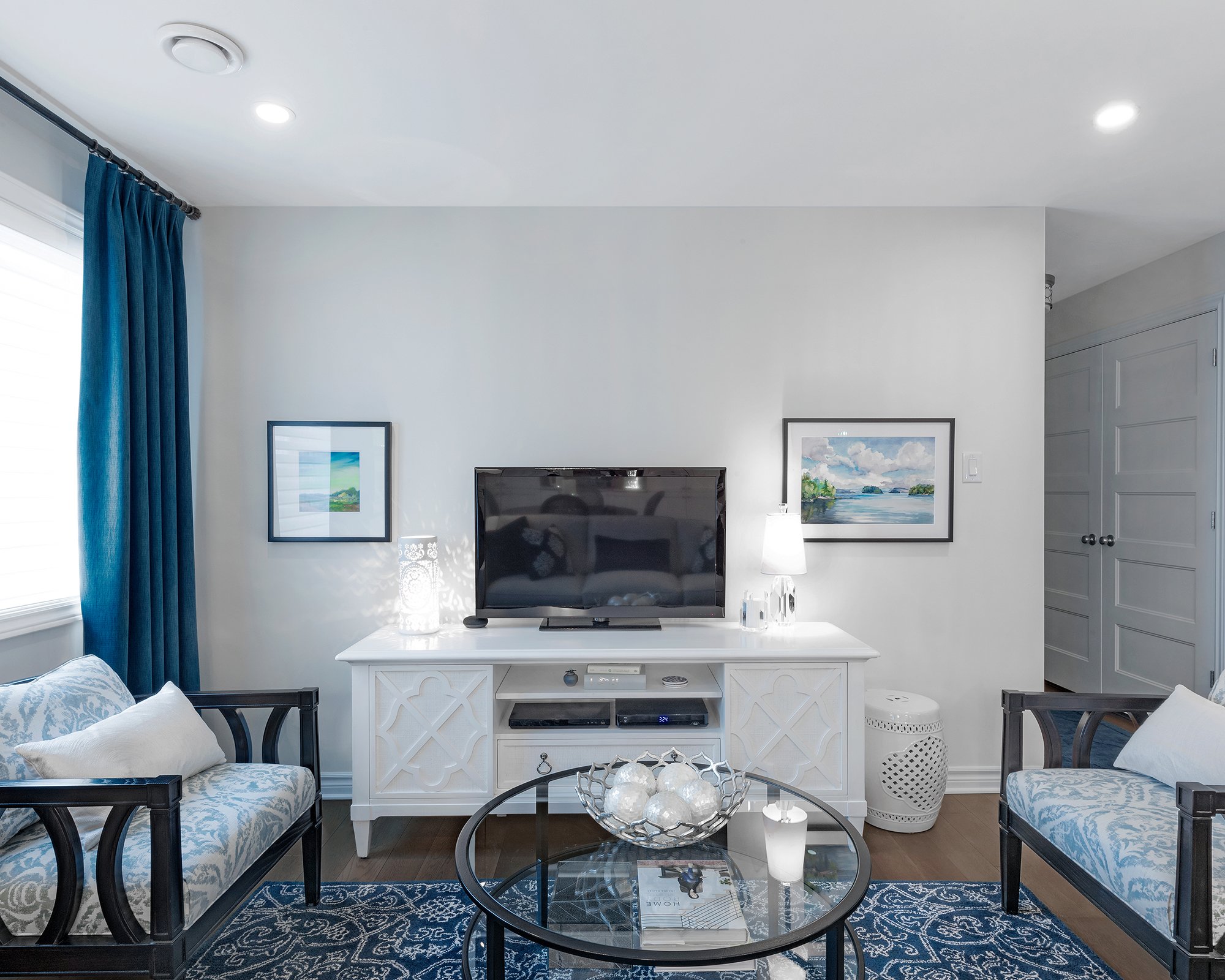Condo makeover in Ottawa featuring a blue and white colour scheme with beautiful entertainment unit and a wool tufted area rug. 