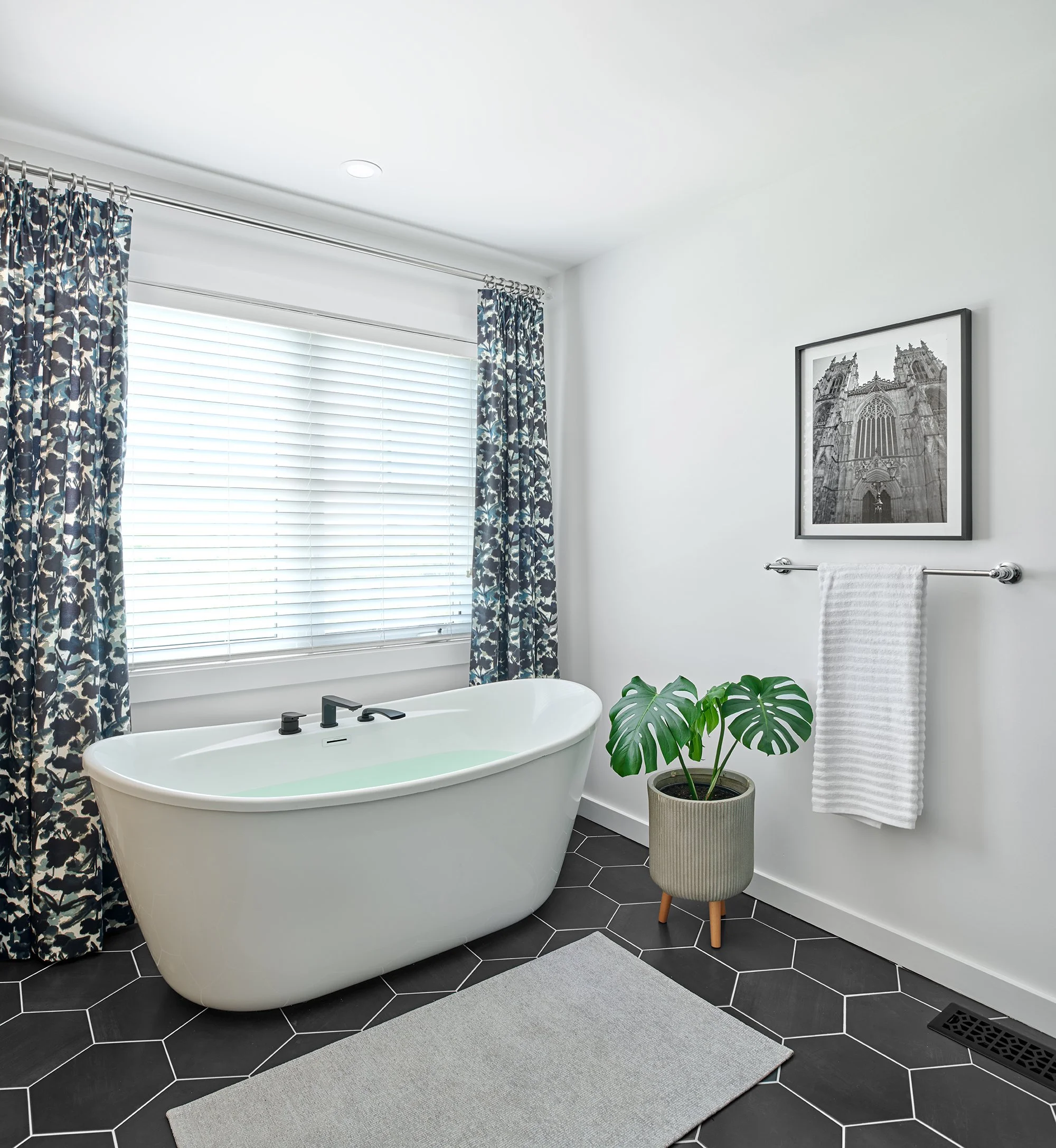 Custom ensuite renovation in Ottawa featuring a freestanding tub, a hexagon tile flooring and beautiful drapery. 