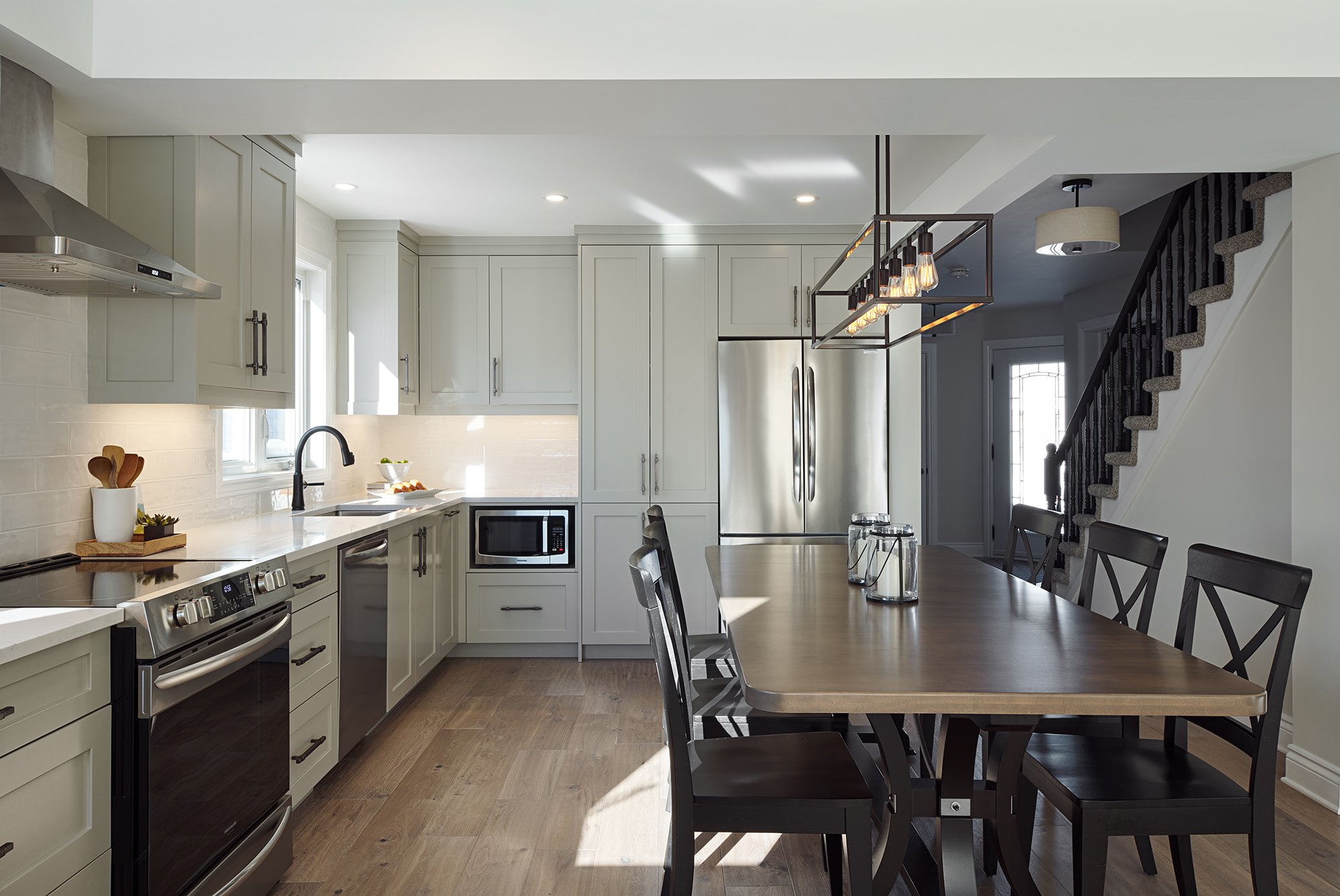 Custom kitchen renovation in Ottawa featuring warm grey shaker cabinets and a farmhouse table. 