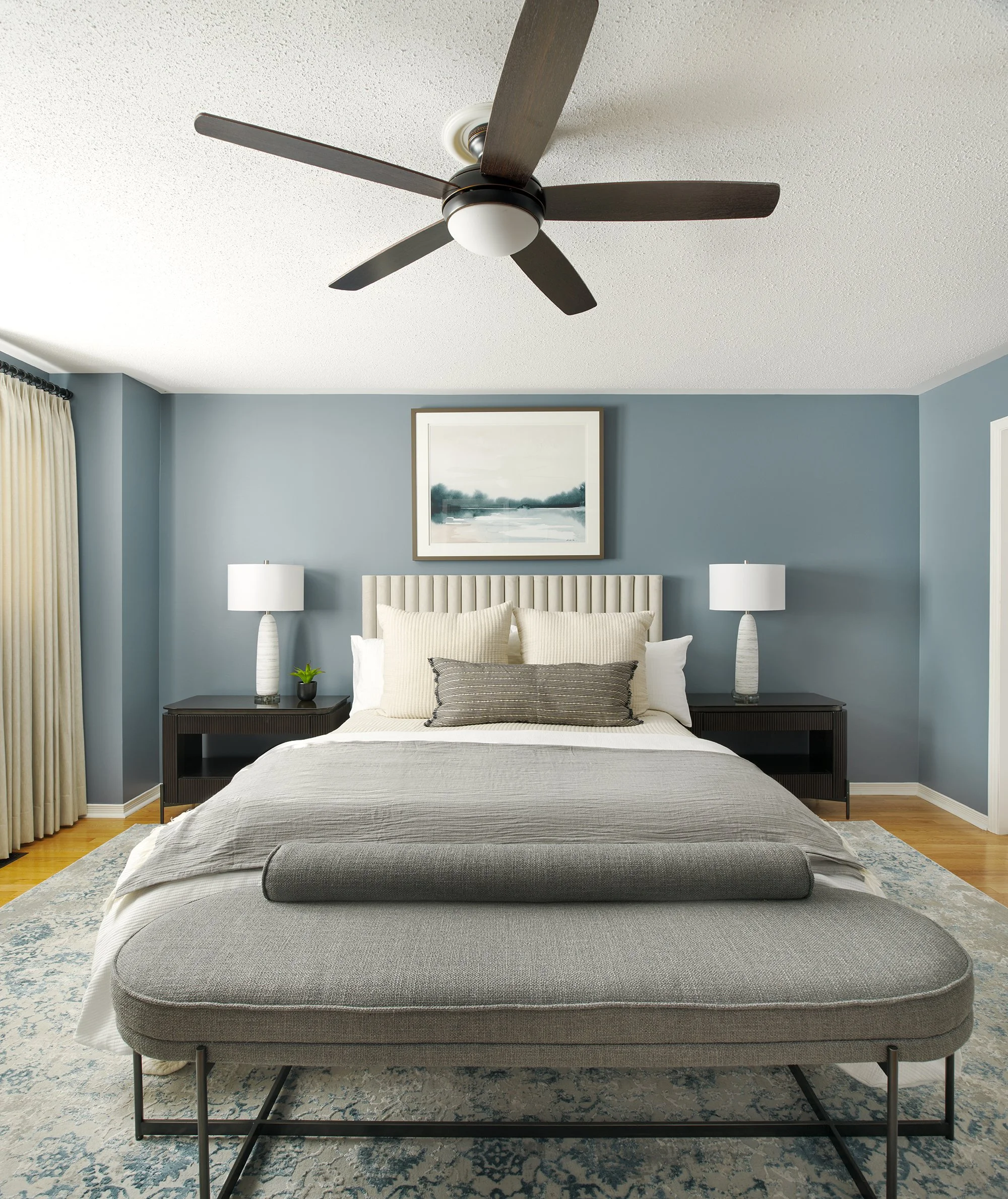 Principal bedroom design in Ottawa featuring an upholstered bed in a soft velvet and rich blue walls. 