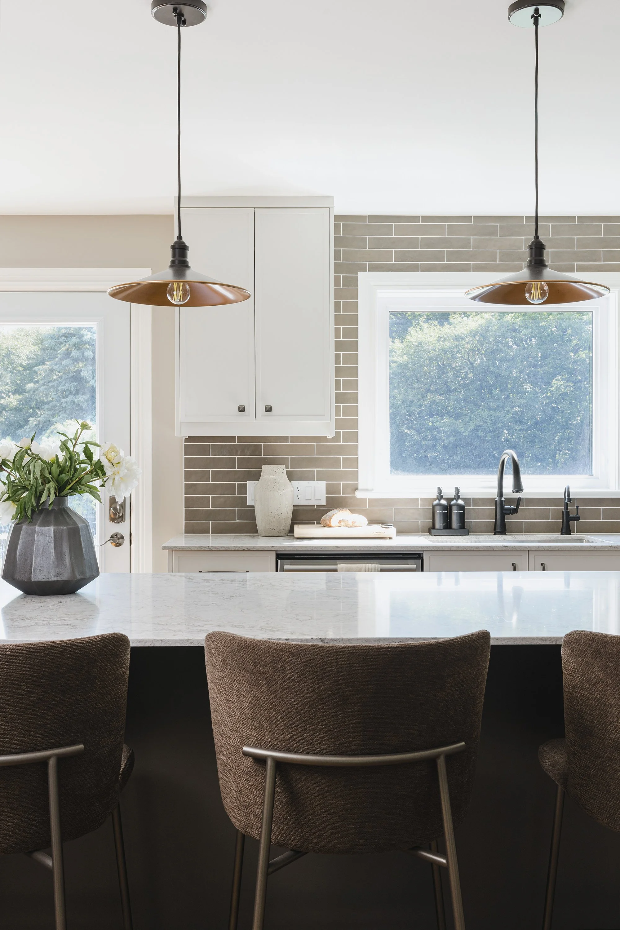 Custom kitchen design for an Ottawa family home featuring light coloured skinny shaker cabinets and unique pendants. 