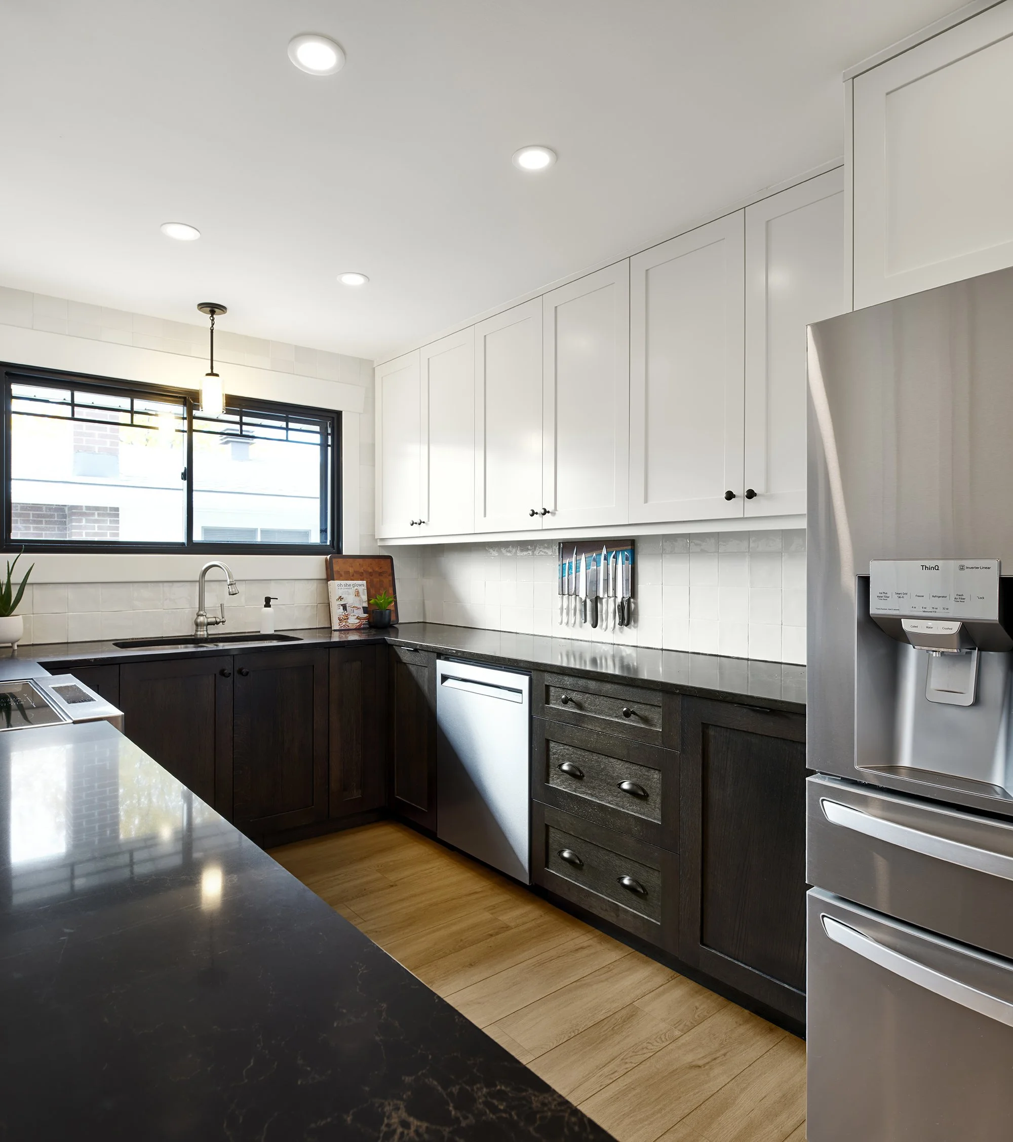 Custom craftsman style kitchen renovation in Ottawa featuring white shaker upper cabinets, white oak lower cabinets and black quartz counters. 