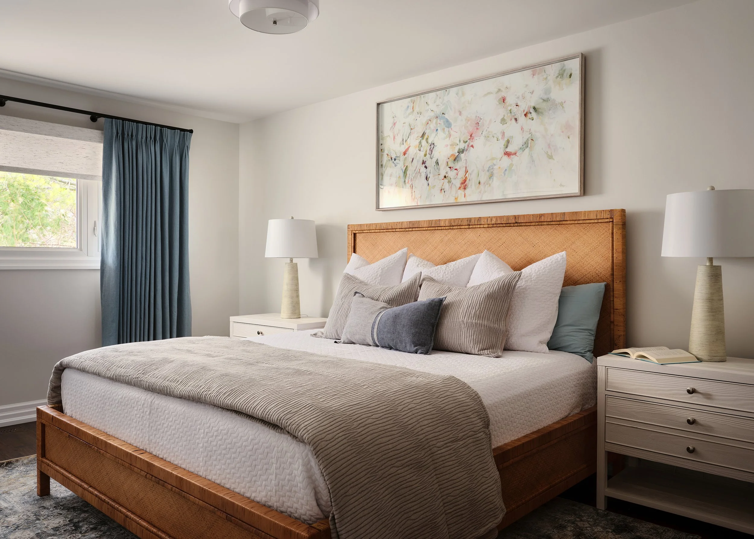 Principal bedroom renovation for an Ottawa family home featuring a woven bed frame and blue drapery.