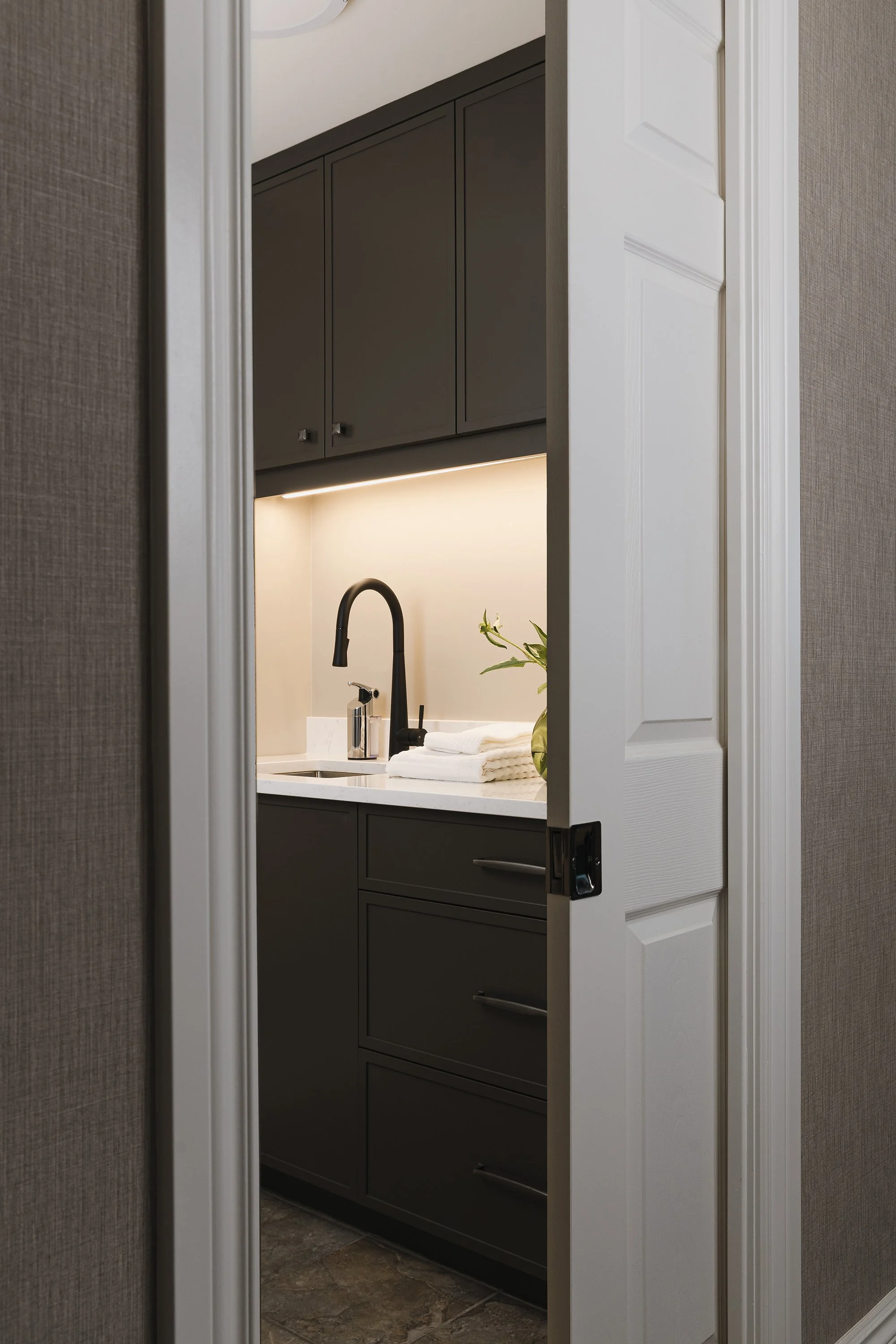 Laundry room design for an Ottawa family home featuring a new laundry sink and under cabinet lighting. 