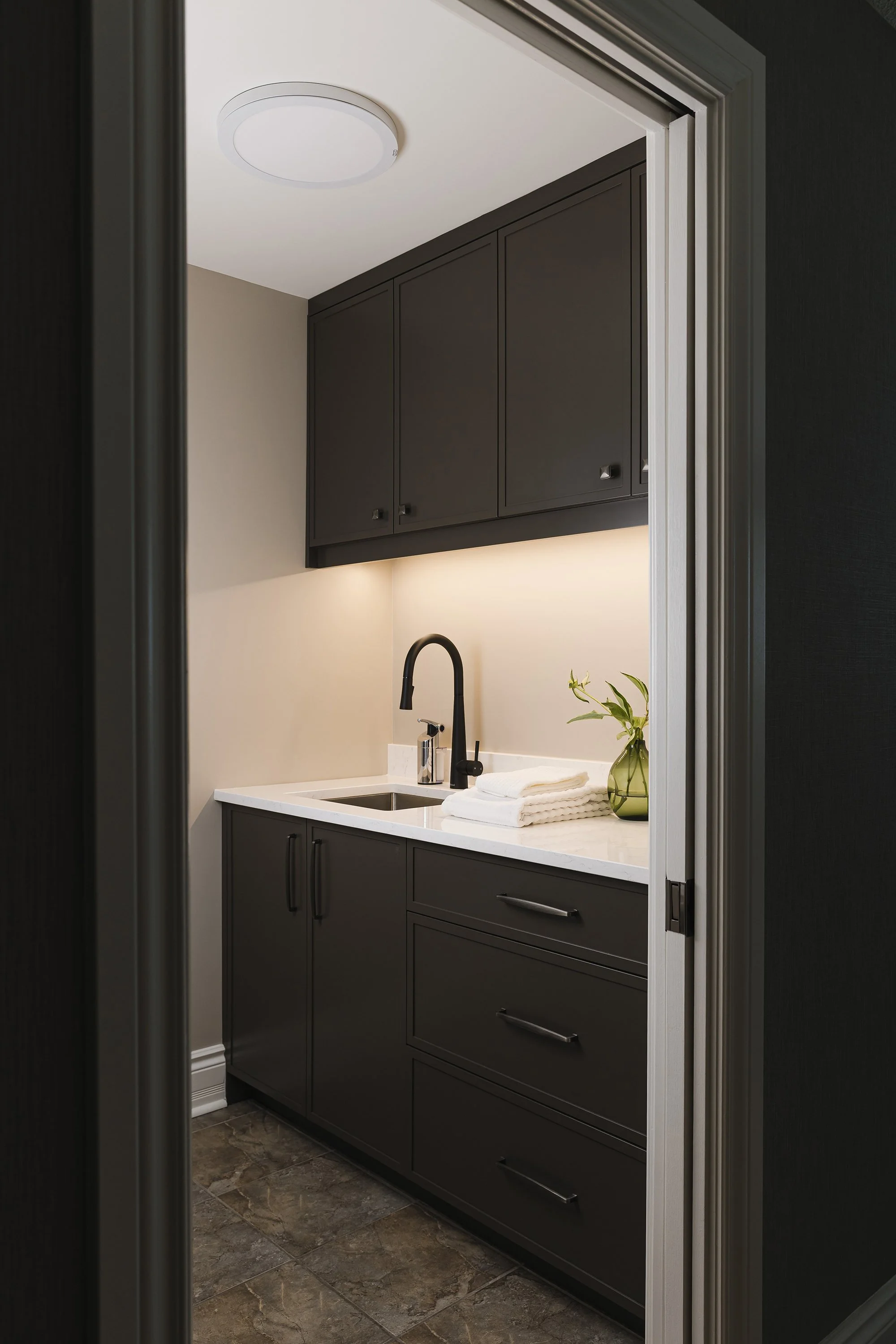 Laundry room design for an Ottawa family home featuring a pocket door and custom cabinets.