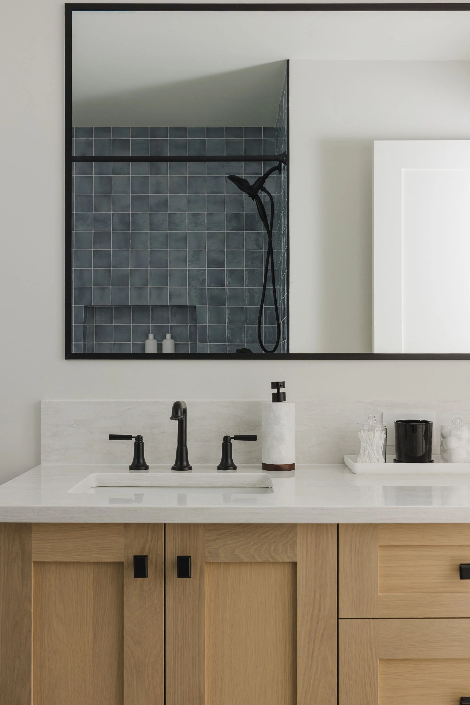 Bathroom renovation in Ottawa featuring a large white oak vanity with double sinks and blue tile in the shower. 