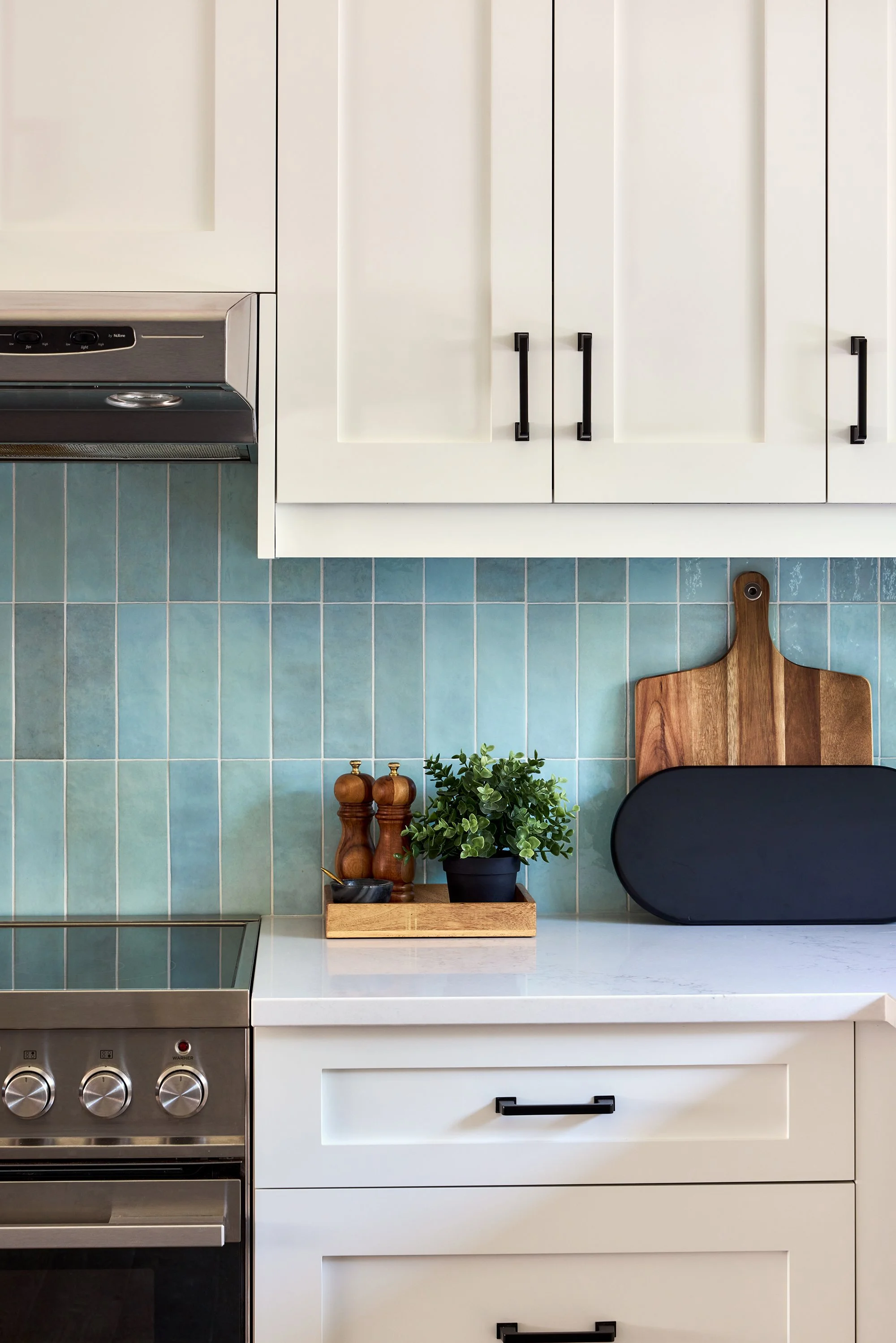 Open concept custom kitchen design for an Ottawa family home featuring white shaker cabinets and a backsplash installed vertically stacked. 