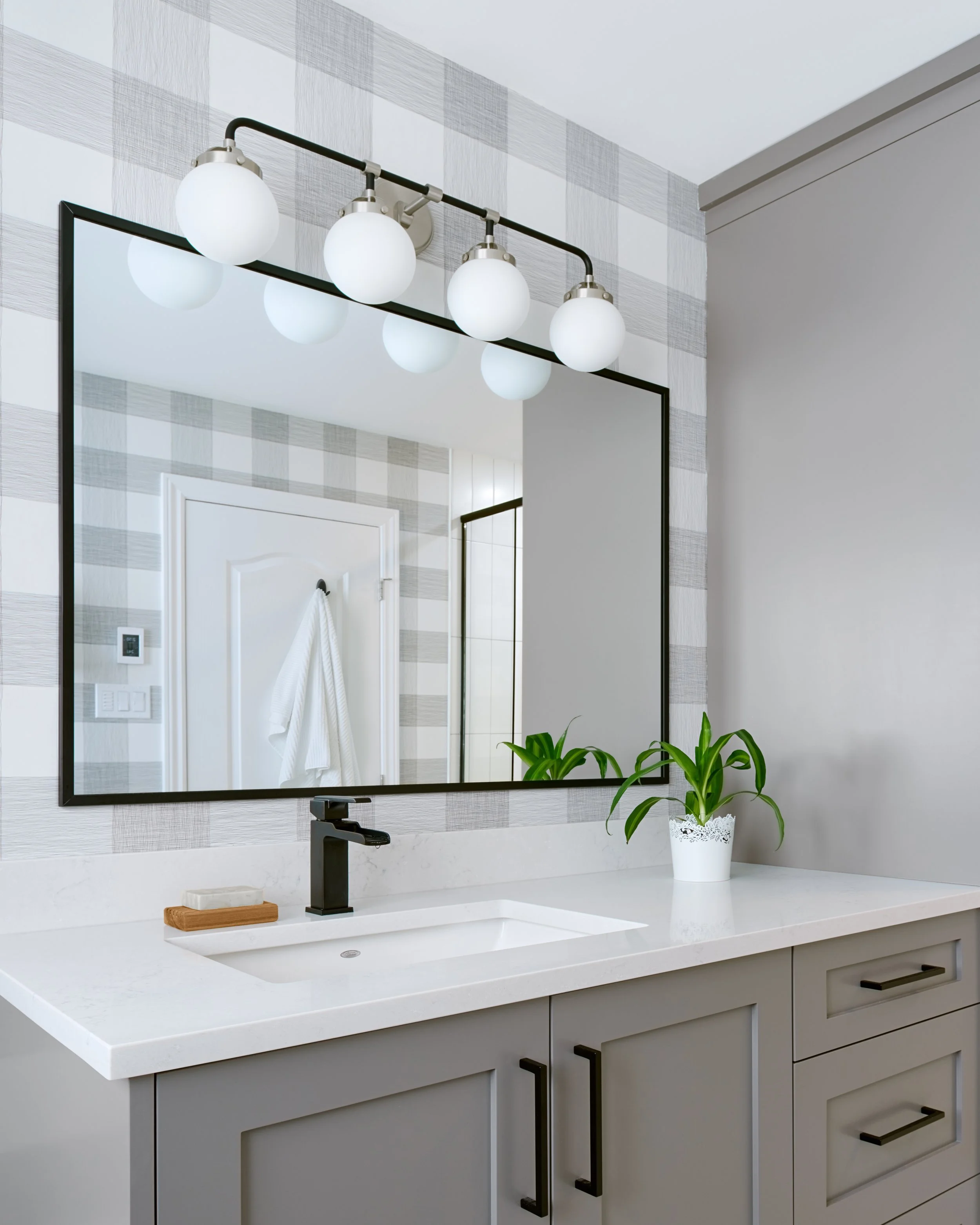 Ensuite bathroom renovation in Ottawa featuring custom grey vanity with black plumbing fixtures and accessories. 