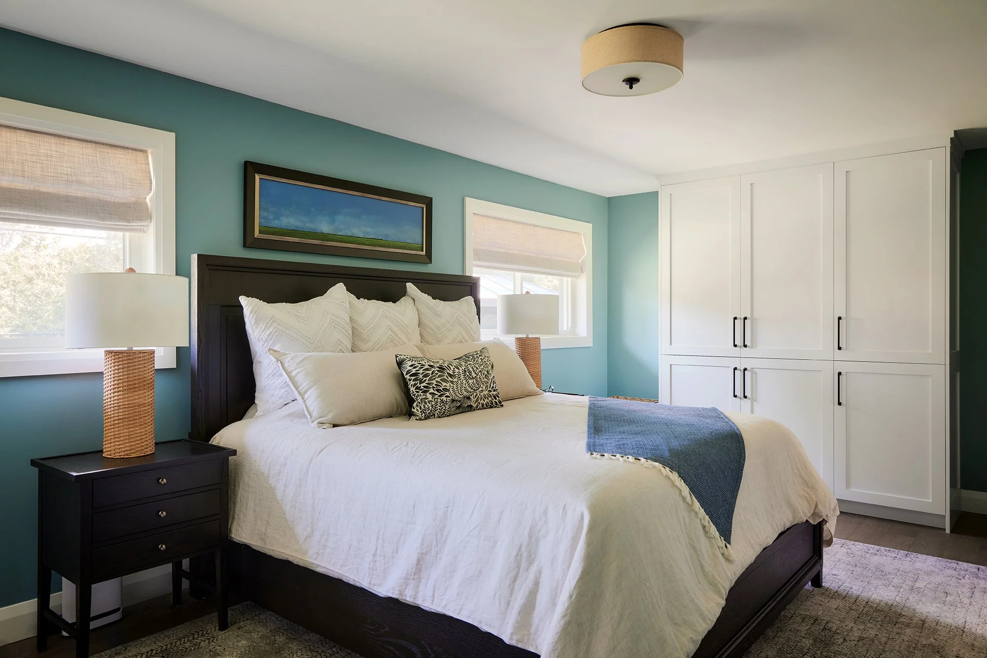 Principal bedroom design for an Ottawa family home featuring a wood bed frame and nightstands, linen bedding and custom closets.