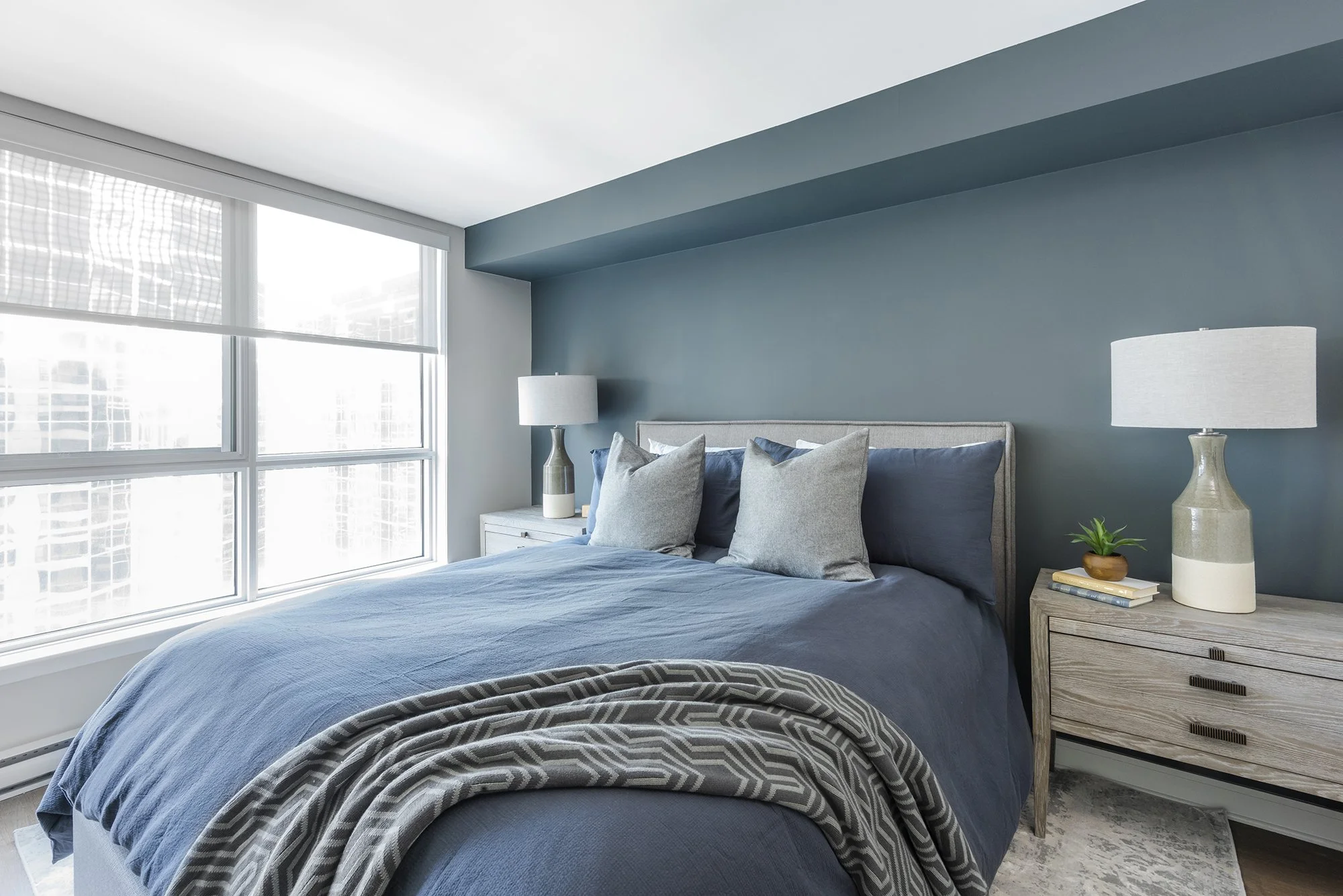 Ensuite bedroom makeover in Ottawa featuring an upholstered bed frame and large grey washed nightstands. 