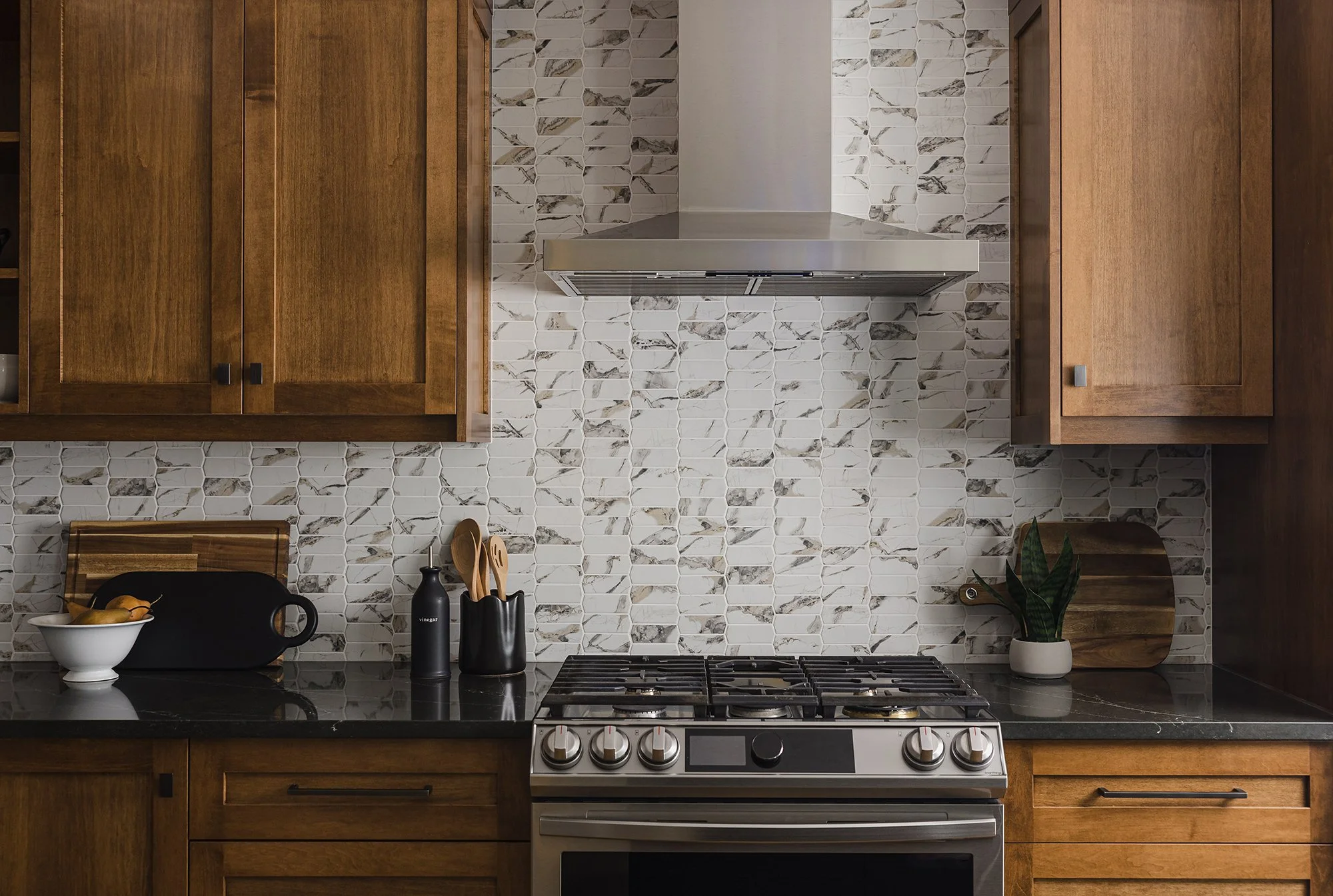 Custom kitchen renovation in Ottawa featuring warm maple cabinets with an exposed stainless hood fan. 