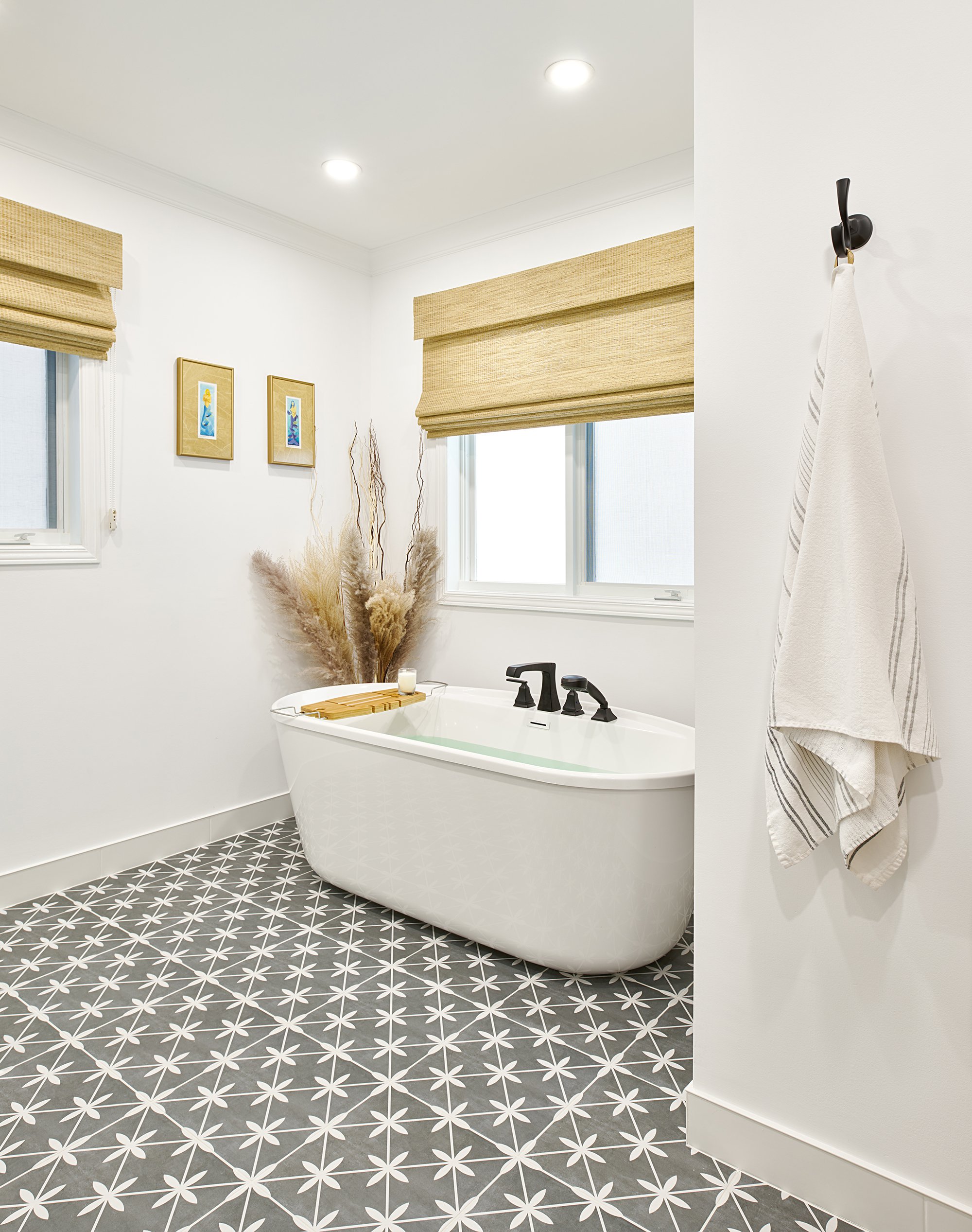 Ensuite bathroom design for an Ottawa family home featuring a patterned floor tile, a deep soaker tub and woven blinds. 