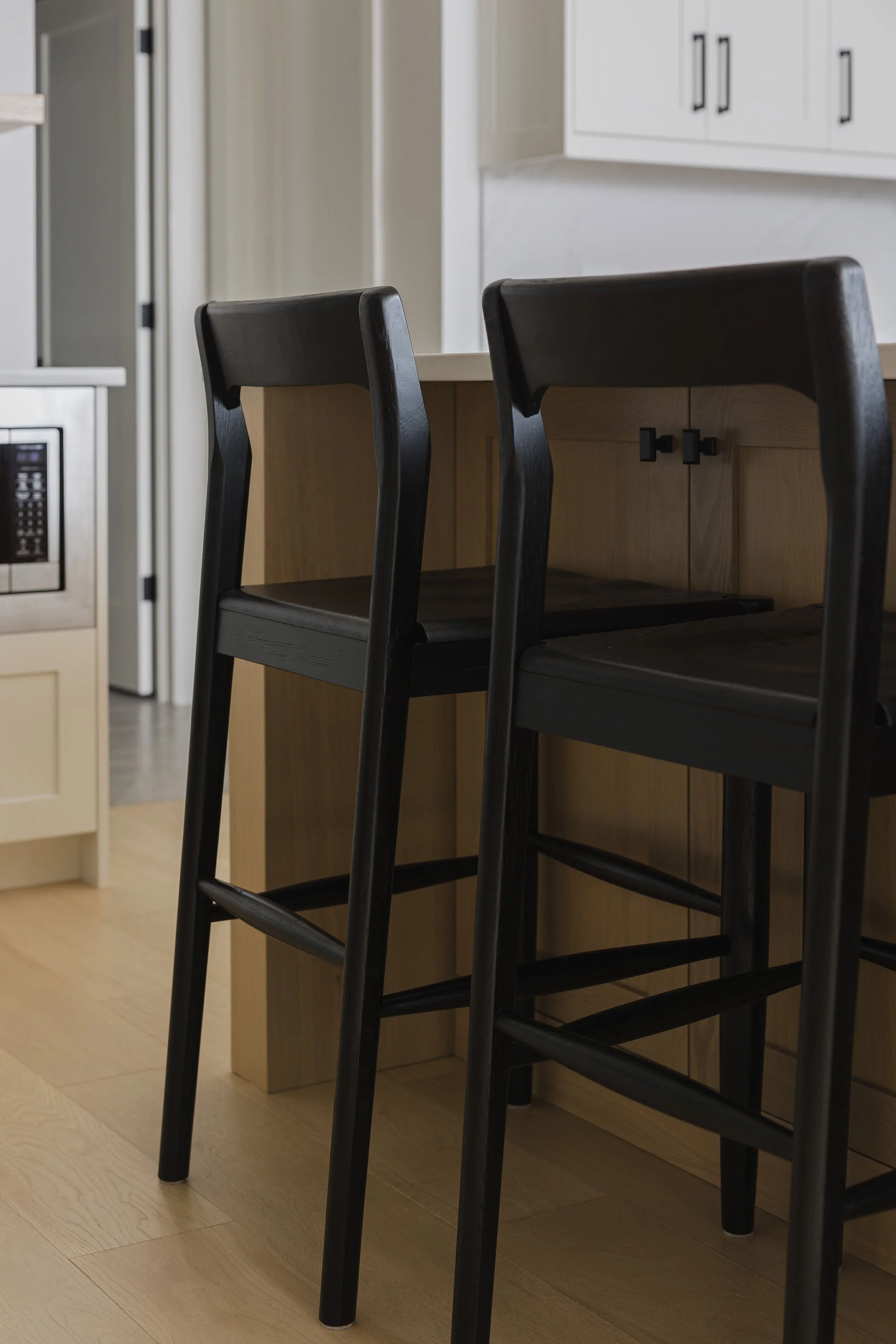 Kitchen renovation in Ottawa featuring white oak flooring and modern black stools.