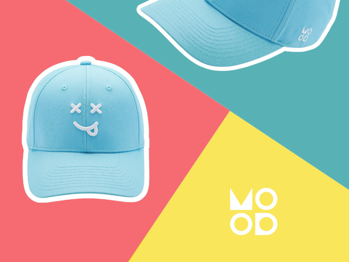 A light blue cap with a cartoon face, tongue out, and X's for eyes, placed on a colorful background with sections in pink, teal, and yellow, with the word 'MOOD' in white letters.