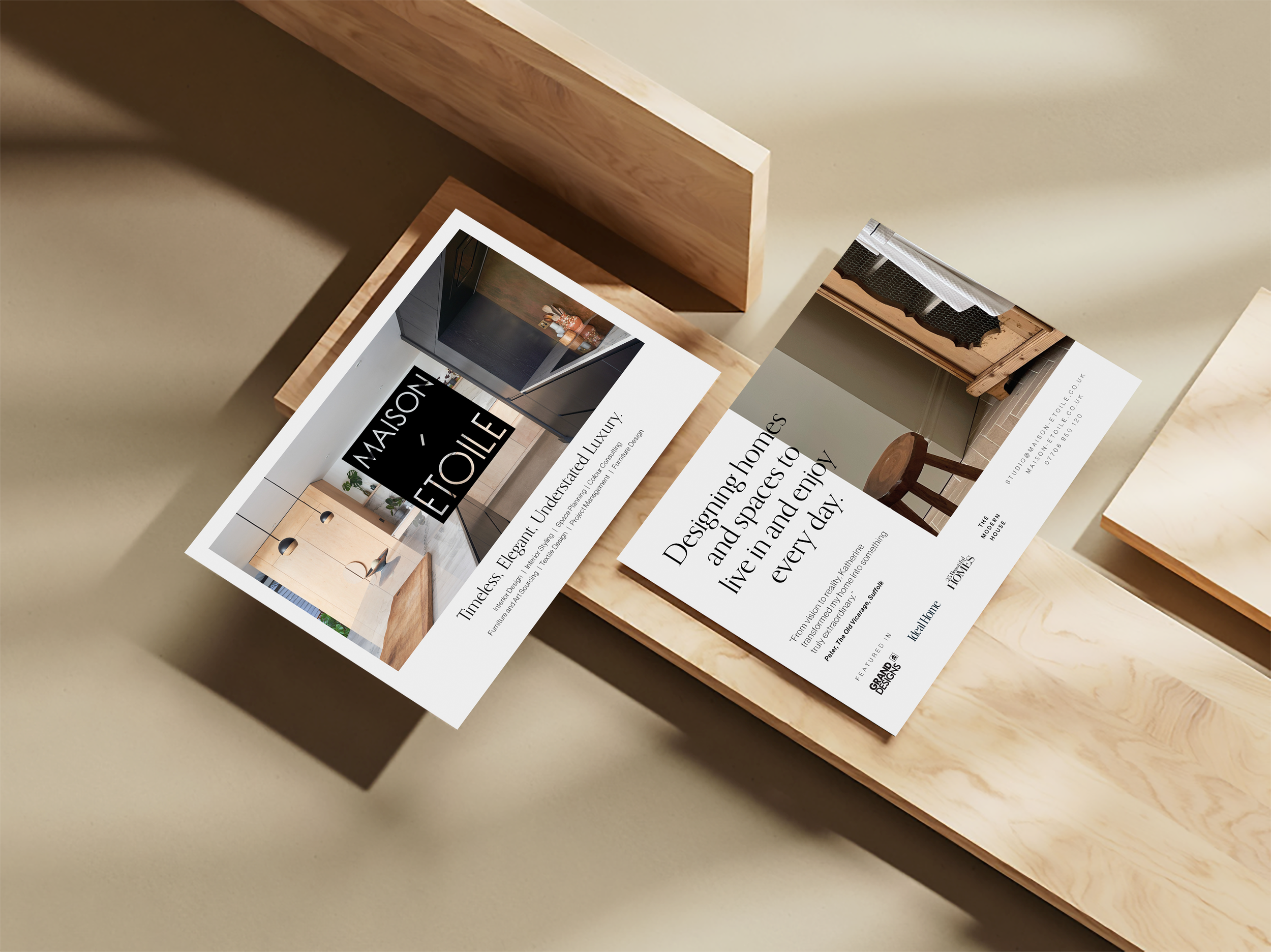 Two real estate flyers on a wooden surface, one showing a modern kitchen interior with text about elegant, timeless homes, and the other featuring a cozy kitchen with a wooden table and a short description inviting to design and enjoy living in a hom