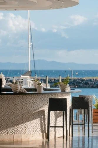 Outdoor bar area with stools, overlooking the ocean with a sailboat and distant islands