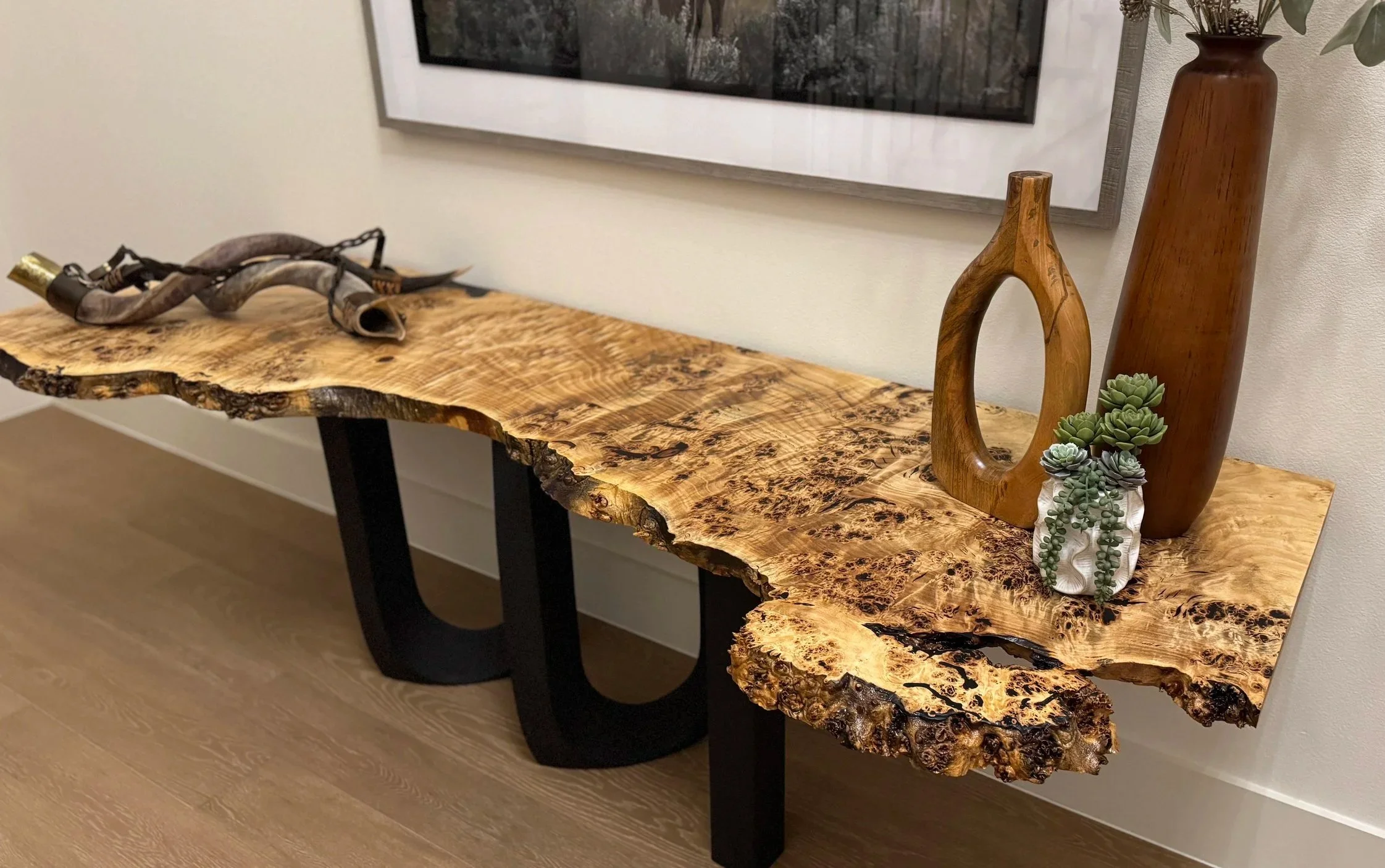 This incredible live edge table is eight feet long and made from an exotic mappa burl wood slab. It's paired with a steel base and filled with black epoxy.