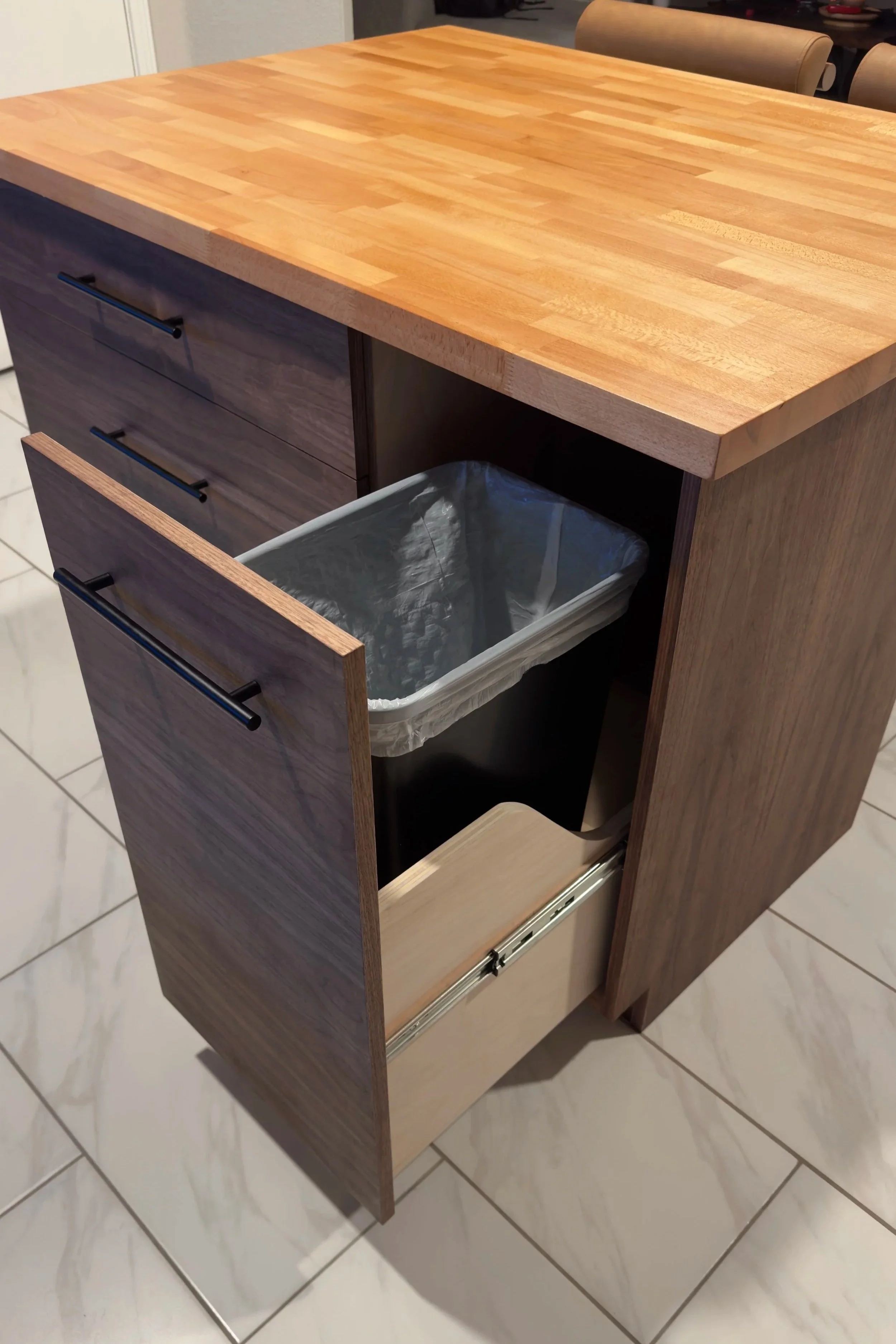 Open kitchen drawer with a trash bin inside.