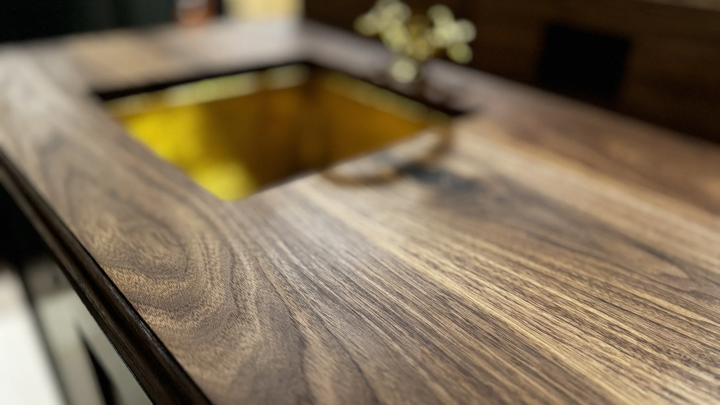 Close-up of natural walnut grain surrounding brass bar sink