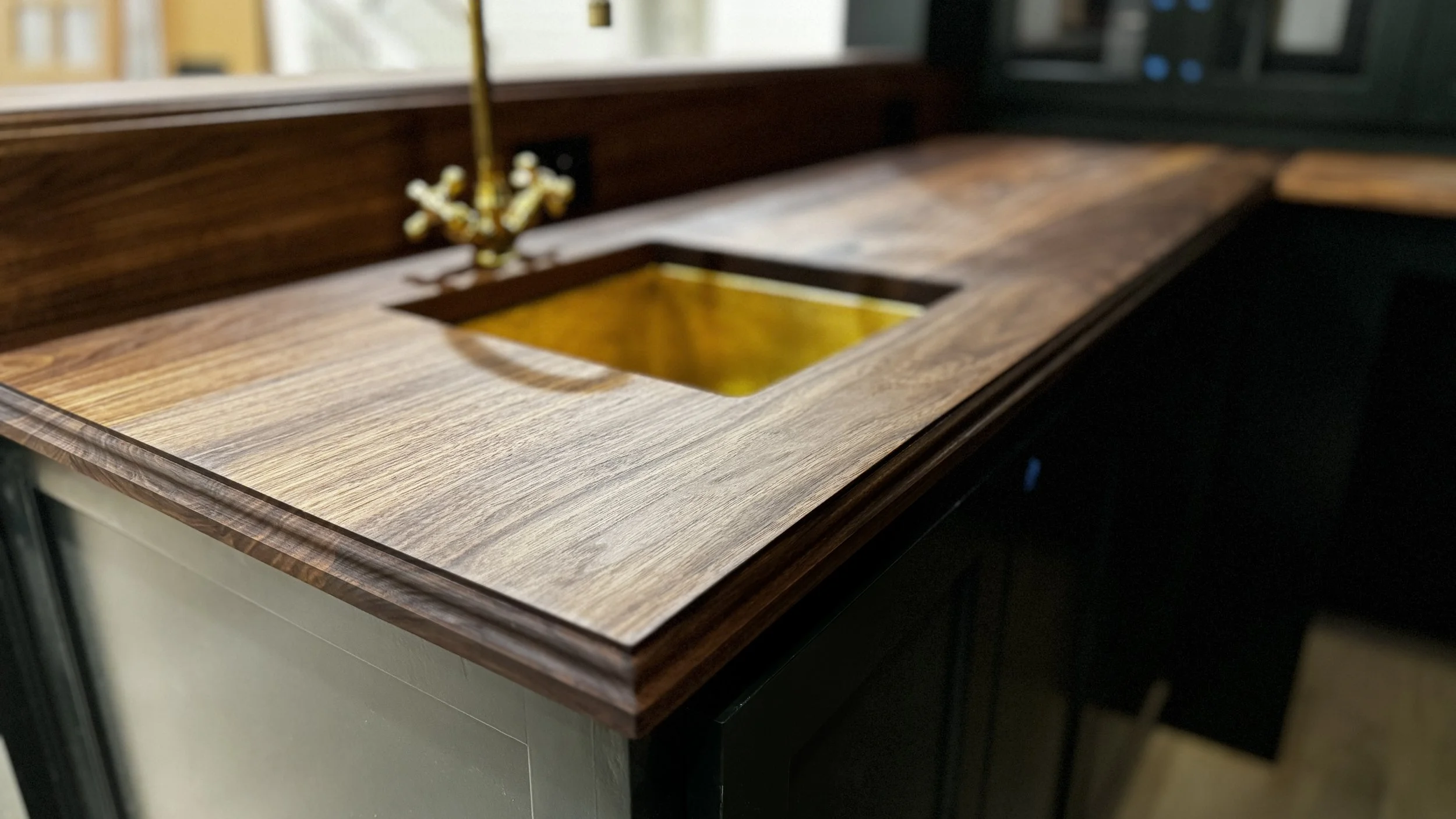 Custom walnut bar countertop with roman ogee edge and brass sink in Fort Worth home