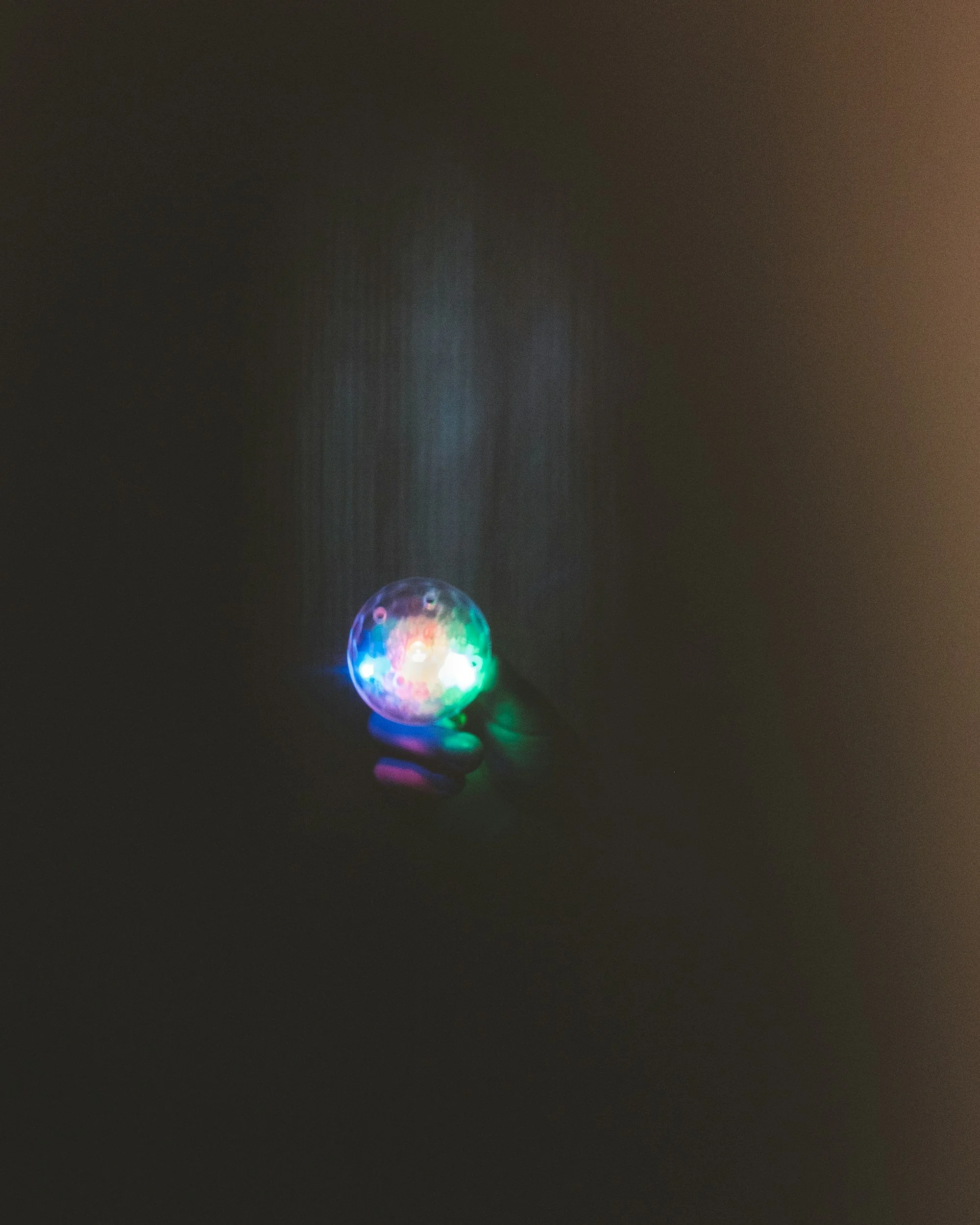 Person holding a sphere with colorful LED lights in a dark room.