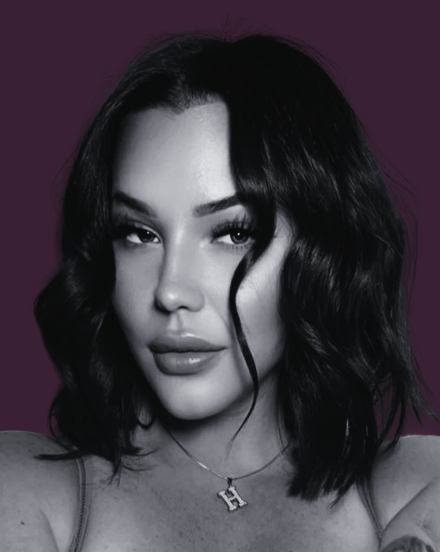 A black and white portrait of a woman with wavy dark hair, wearing a necklace with a pendant and a top with thin straps, against a dark purple background.