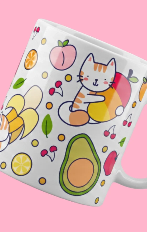 A white mug with colorful illustrations of a cat hugging a fruit, avocados, lemon slices, cherries, bananas, and other fruit and food items on a pink background.