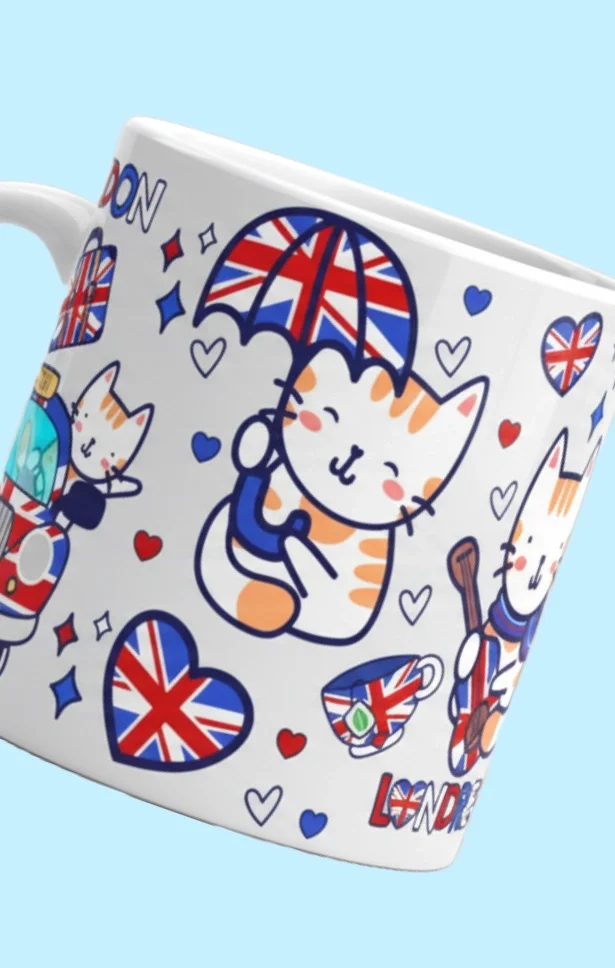 A white ceramic mug decorated with cartoon cats, Union Jack flags, hearts, and the word 'LONDON.'