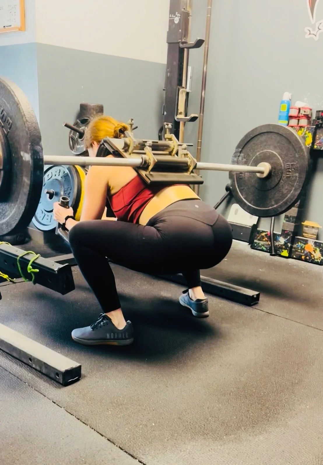 Woman doing squats with a barbell fitted with the Squat Baby attachment
