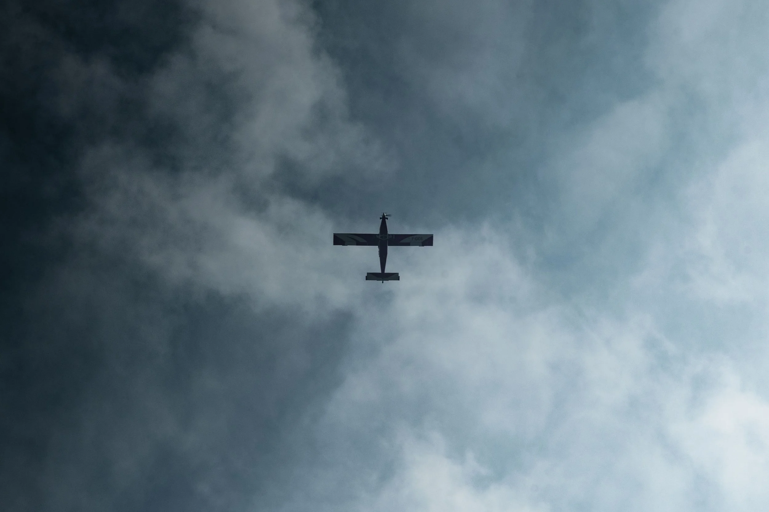 Un avion de petit format vole dans un ciel nuageux.