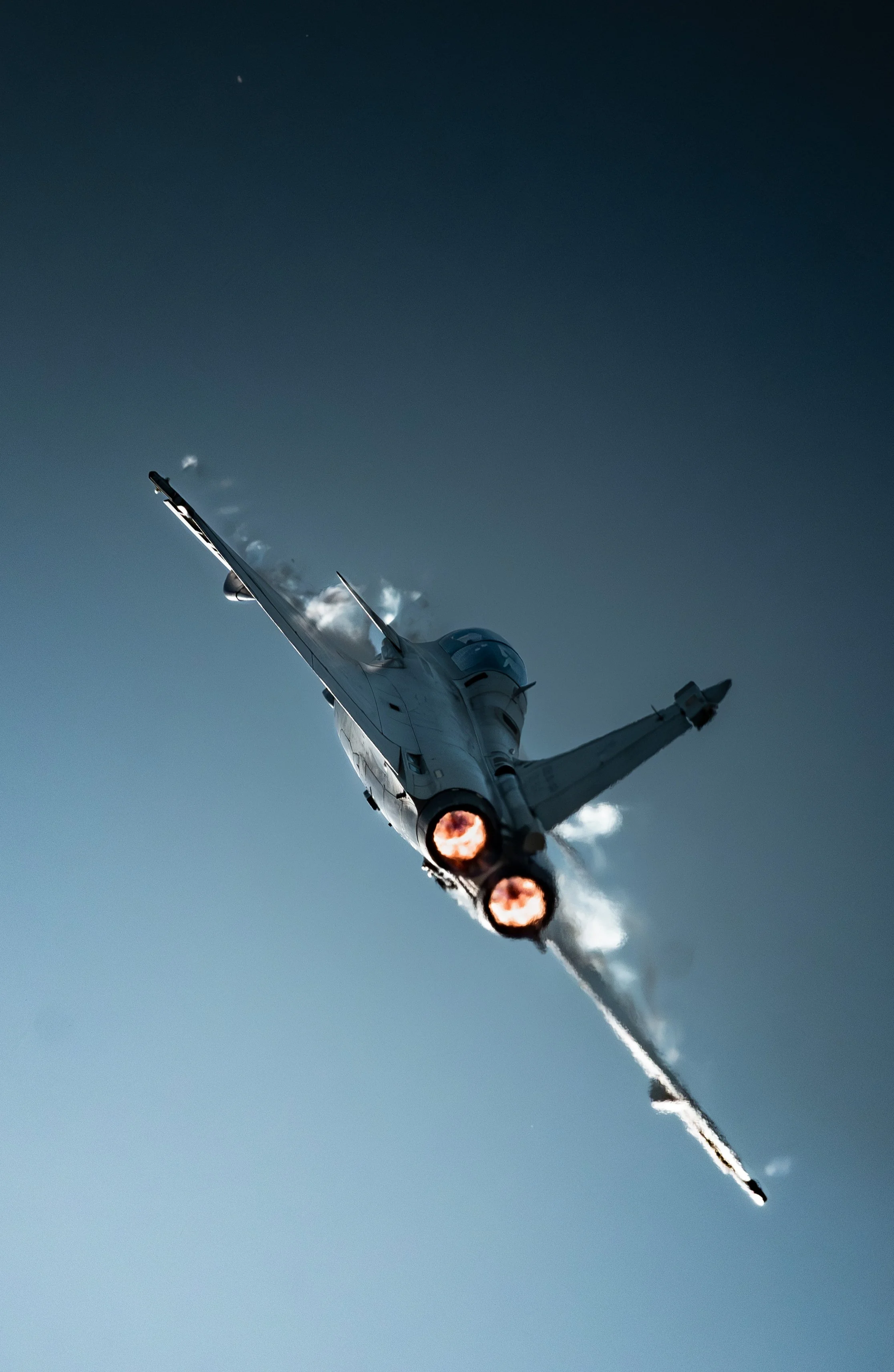 Un avion de chasse Rafale B, Rafale solo display RSD Français en vol avec ses moteurs à combustion visible et d'épaisses traînées de vapeur dans le ciel.