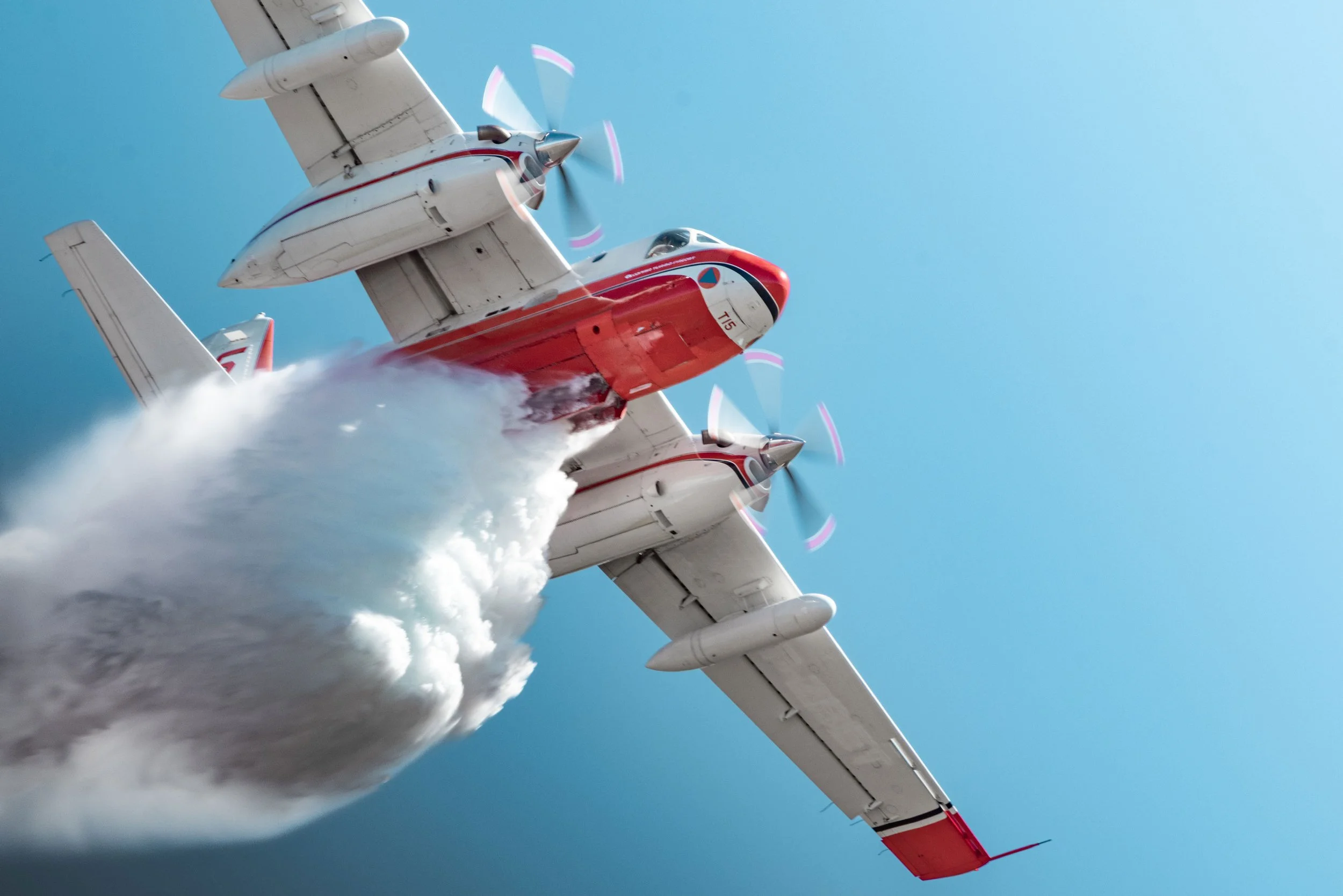 Un avion de formation en vol effectuant un passage en formation, laissant derrière lui une traînée blanche, avec un ciel bleu clair en arrière-plan.