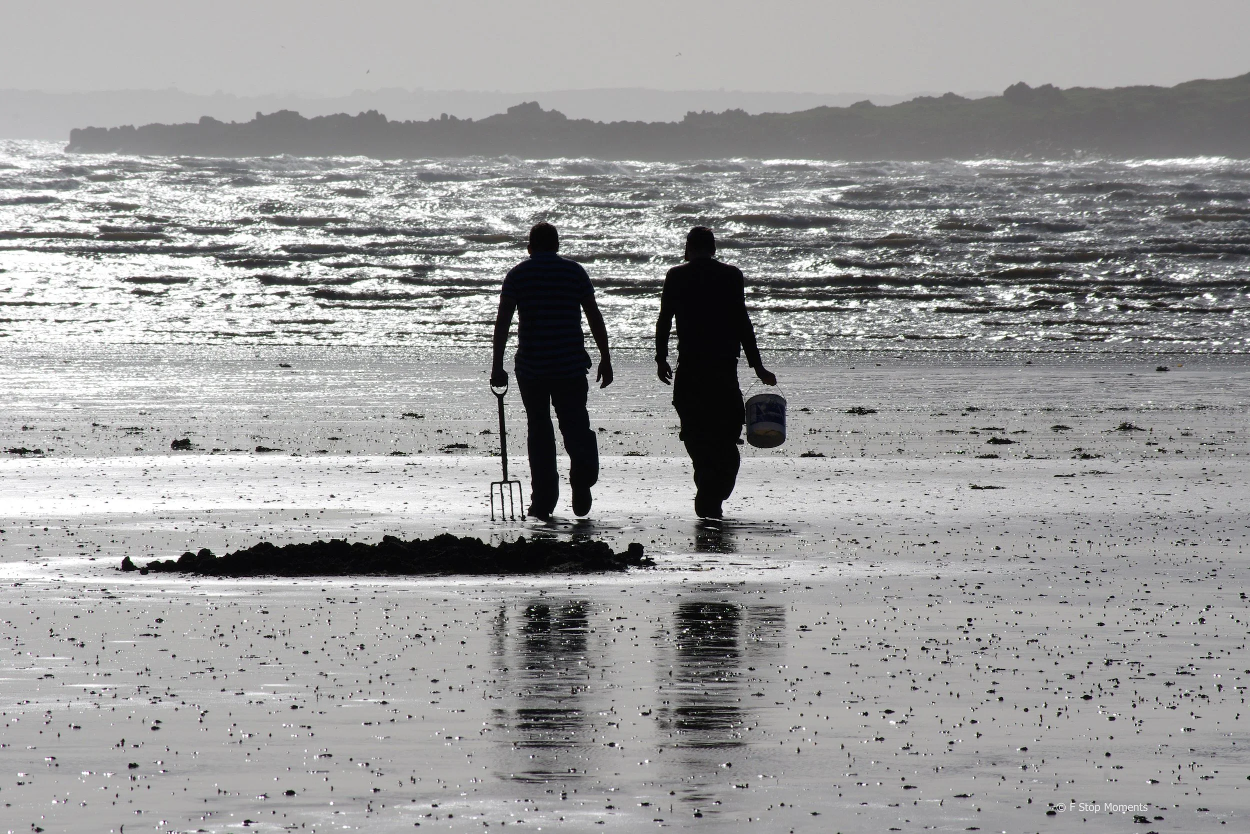 A black and white image of two people beachcombing on the Solway Firth.