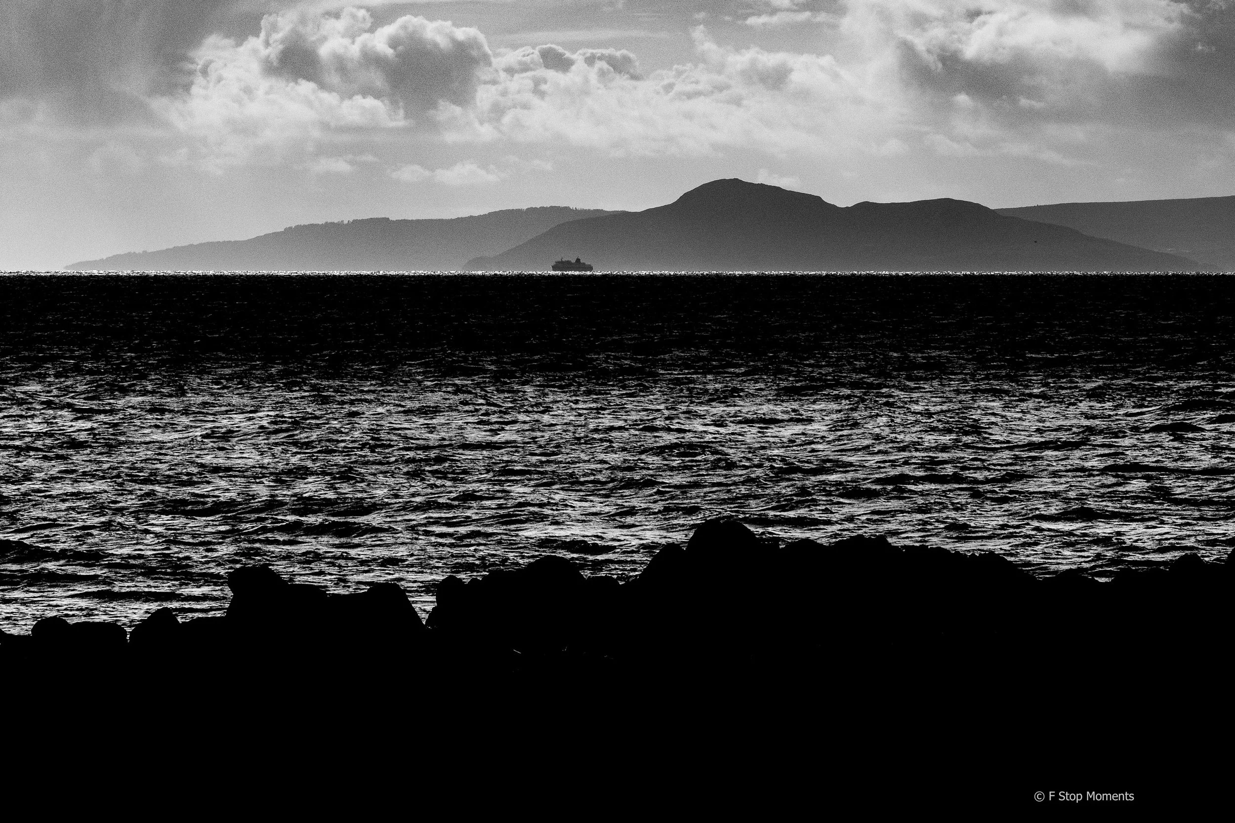 The black and white image of the Isle of Arran, a famous wedding destination, with a silhouette of the ferry in the distance.