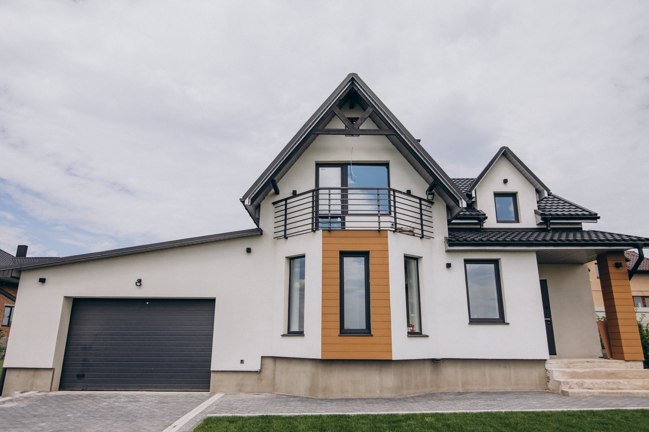 Nieuw modern huis met witte gevel, zwarte raamkozijnen en een boerderijstijl dak, met een garage en een kleine trap voor de ingang.