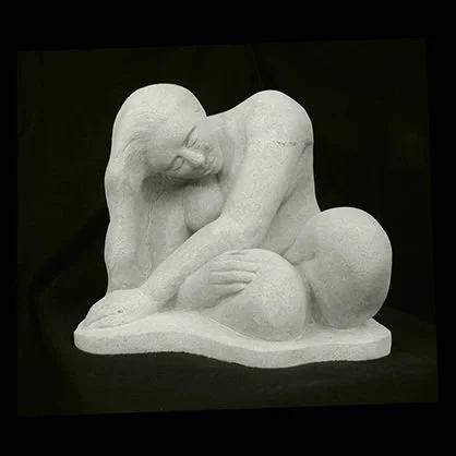 A white sculpture of a nude woman sitting with her head resting on her arm and her legs curled up, on a black background.