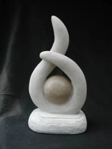 Abstract sculpture with a curved, two-tone structure and a spherical element at the center on a flat base.