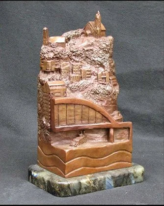 A detailed miniature sculpture or model of a carved bas-relief scene with a bench and stairs, set on a small marble base.