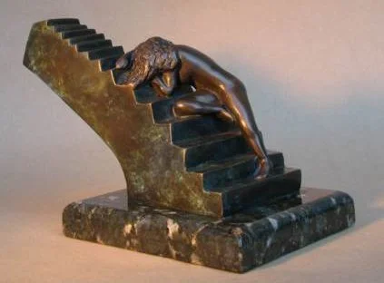 Sculpture of a hand reaching out and touching a stepped black and gold structure