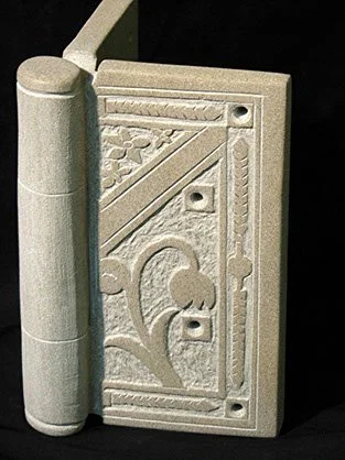 Close-up of a decorative, carved stone door hinge with floral and geometric patterns.