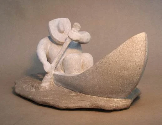 A small sculpture of a fisherman sitting with a hat, holding a fishing pole, and a large fish next to him.