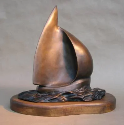Bronze sculpture of a sailboat on a wooden base.
