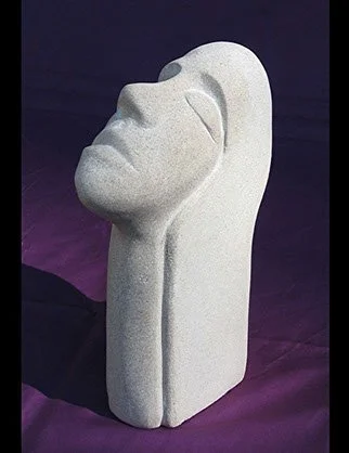 Sculpture of a human face with closed eyes, profile view, on a purple surface.