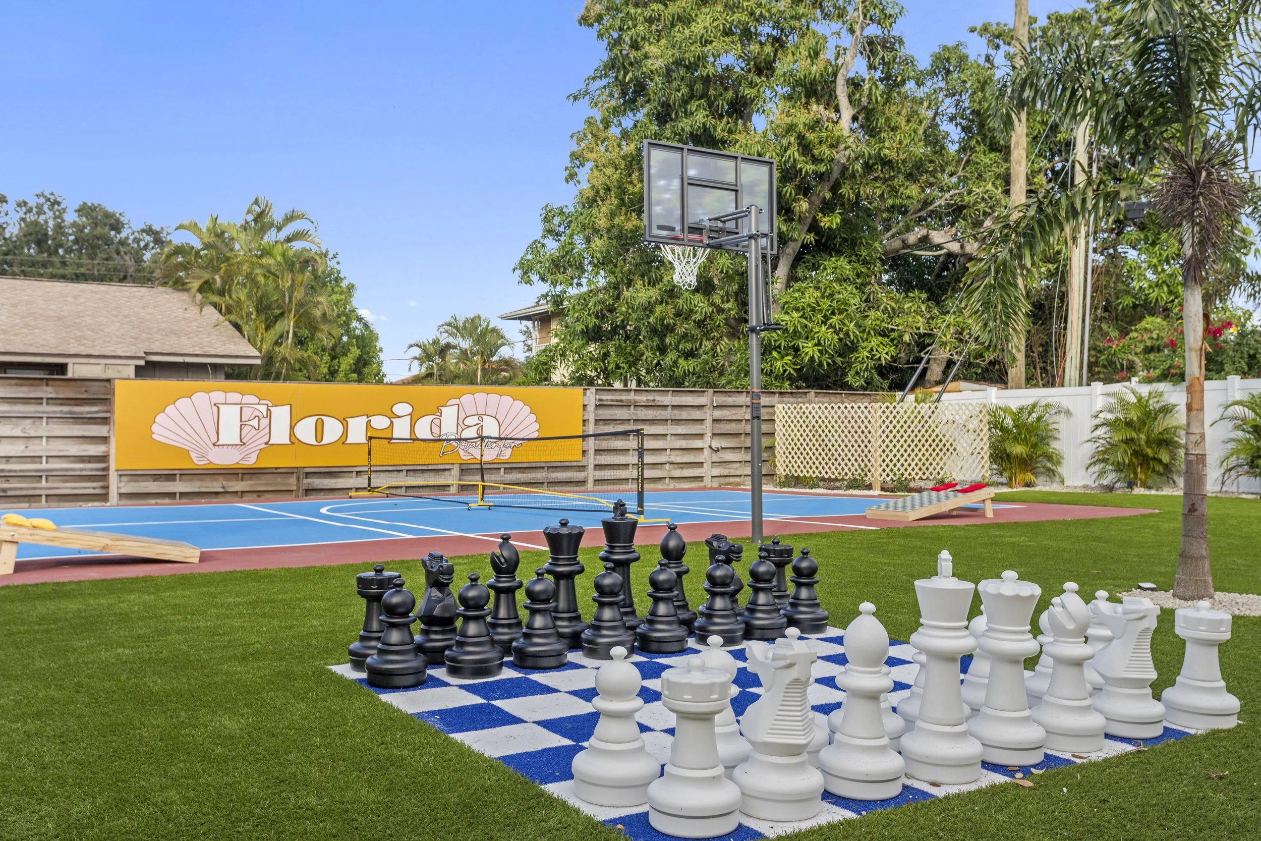 Backyard with giant chess set, basketball court, and a Florida-themed sign with seashells