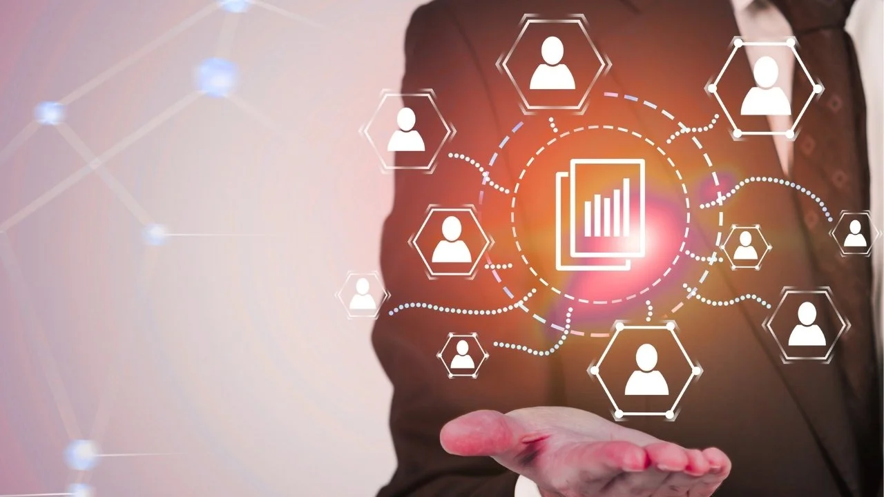 Businessperson's hand extending forward with digital icons of people and a bar chart floating above, representing data analytics and networking.