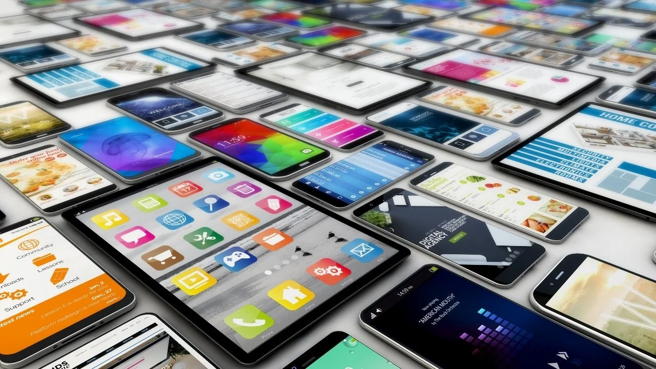 Multiple smartphones displaying various colorful app screens and websites, arranged on a white surface.