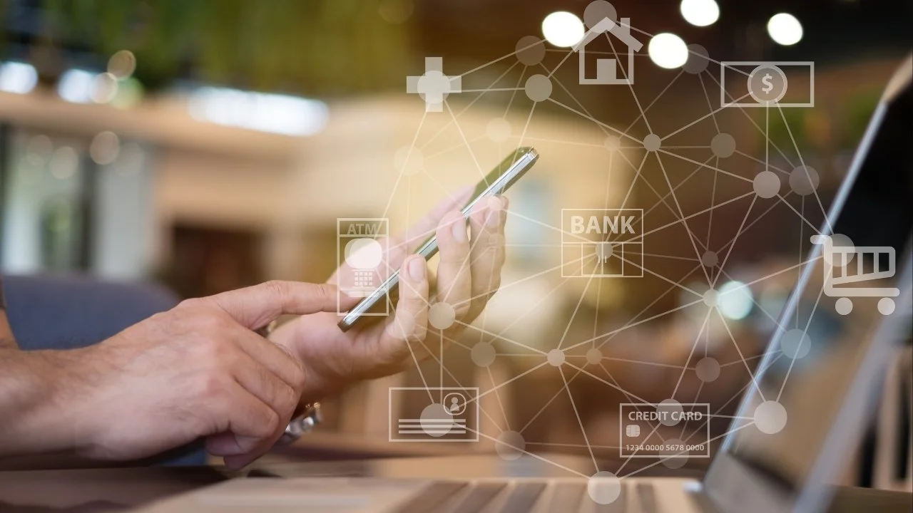 Person using a smartphone with digital icons representing banking, credit cards, ATM, shopping cart, and home overlayed in a network pattern