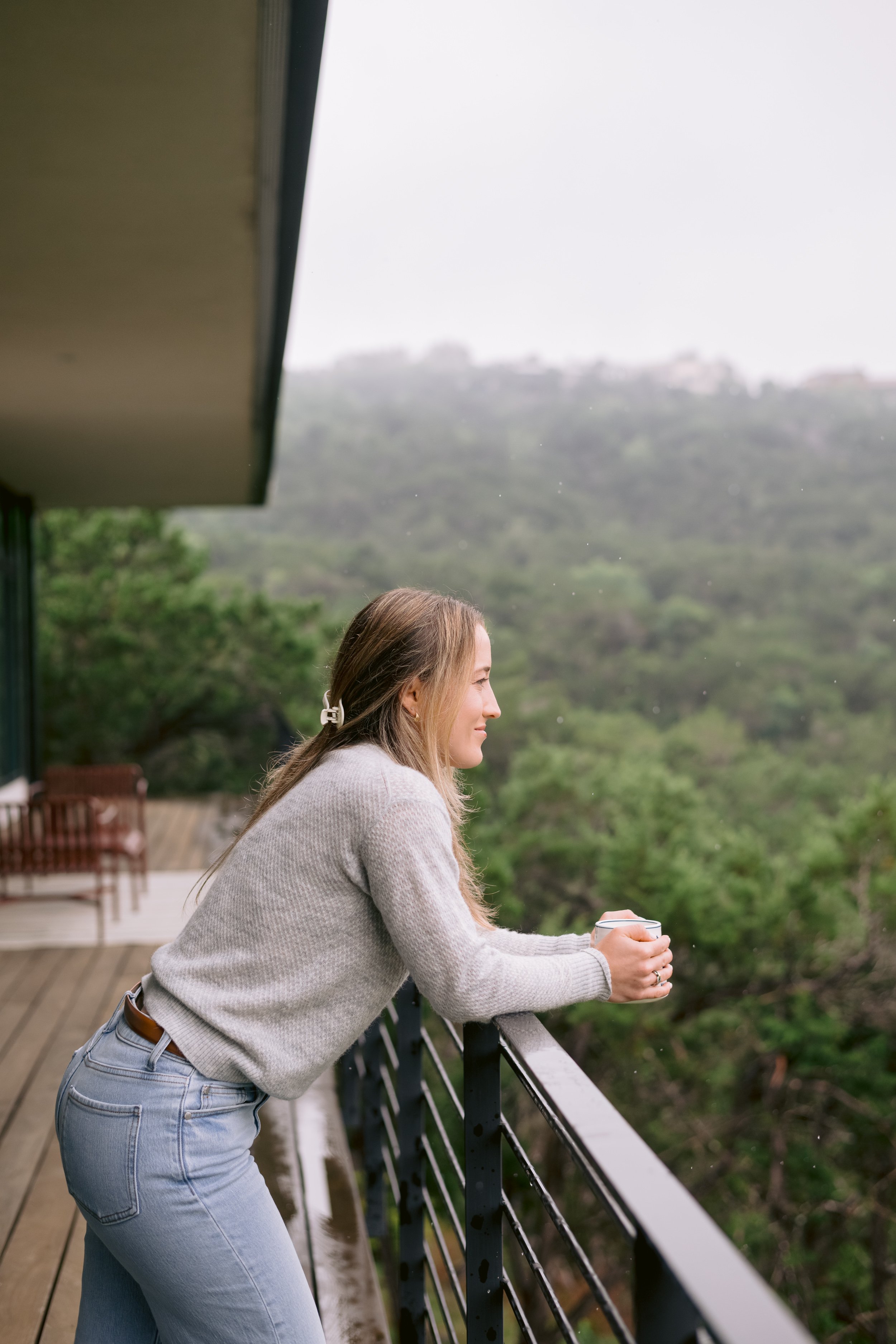 therapist standing on a balcony, holding coffee, looking out at the Texas Hill Country