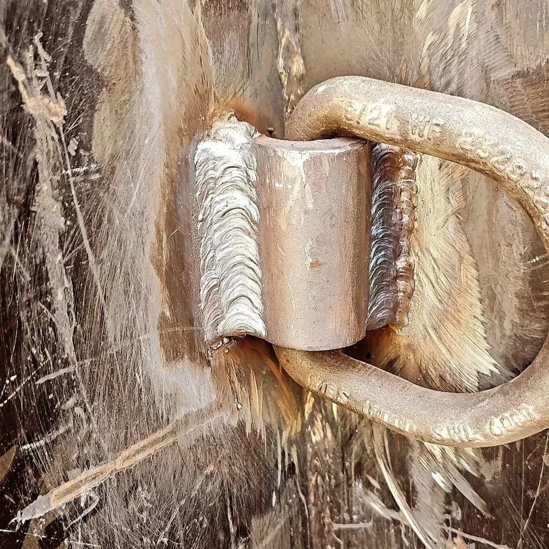 Close-up of a metal hinge and clasp on a scratched, metallic surface.